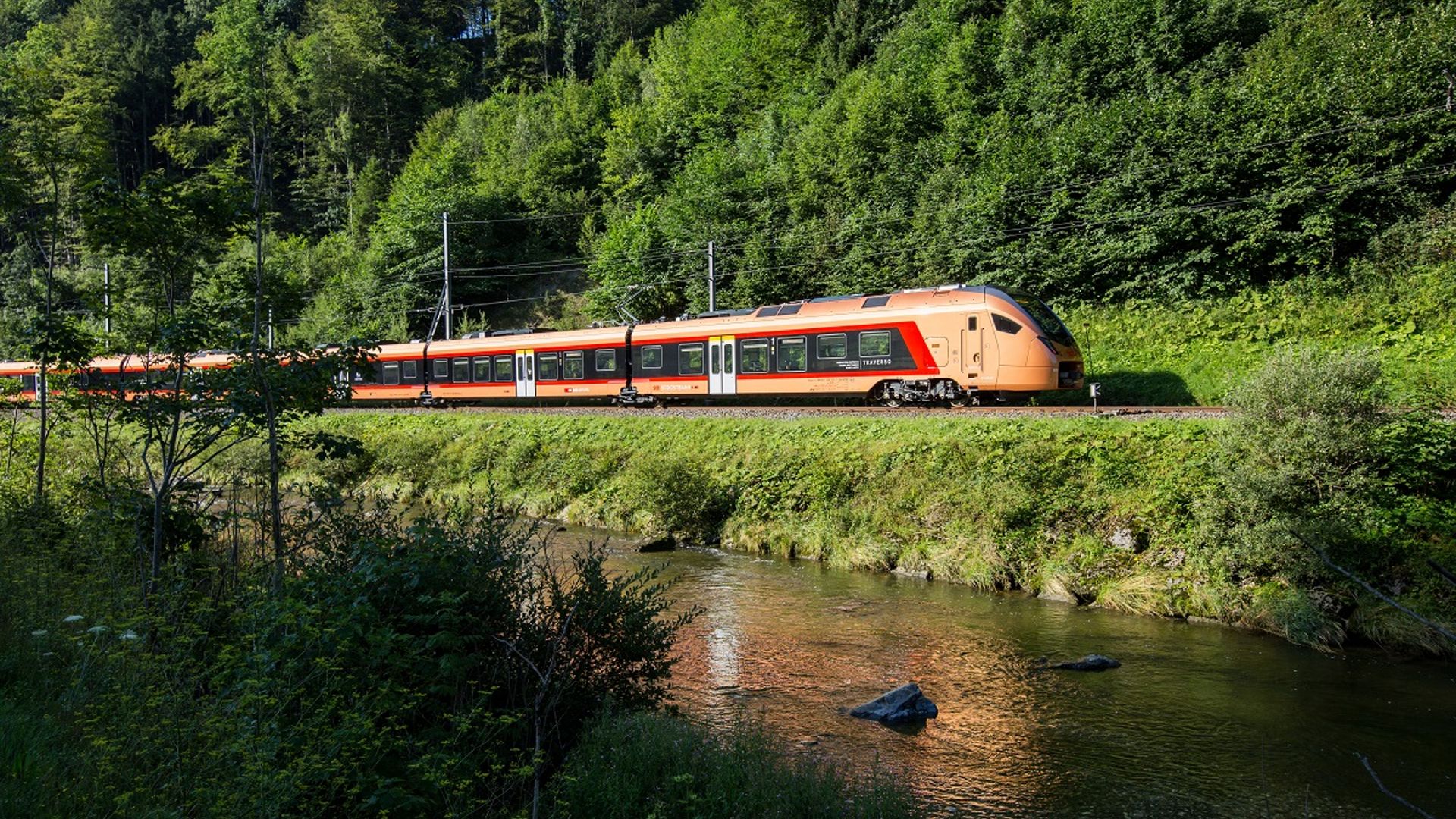 Le Voralpen-Express passe près d’Einsiedeln, longeant un ruisseau au cœur d’un paysage verdoyant.