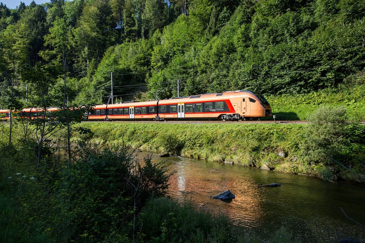 Il Voralpen-Express vicino a Einsiedeln, lungo un torrente immerso nel paesaggio verde.