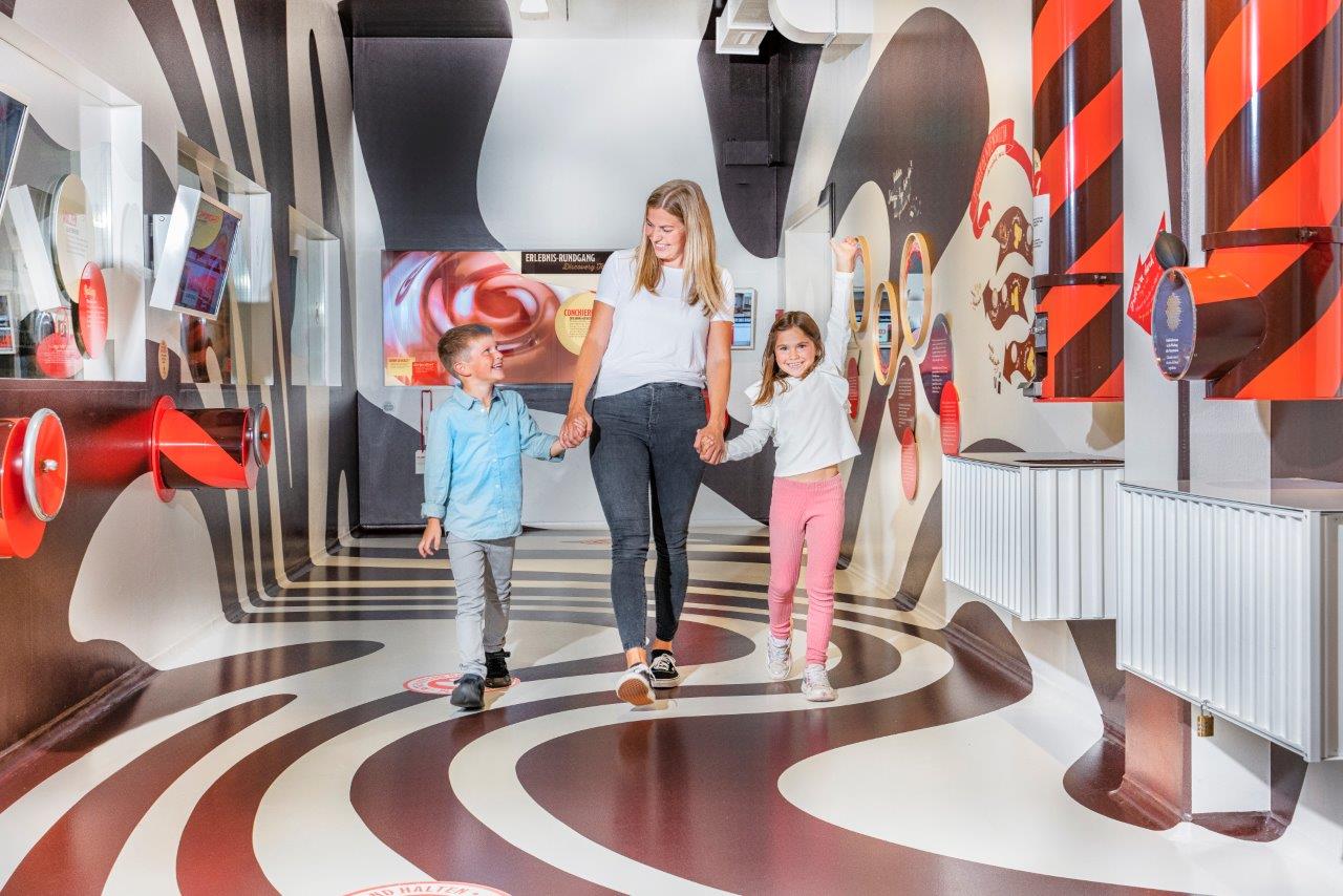 zwei Kinder mit der Mutter in der Mischerei auf dem Erlebnisrundgang des Chocolariums