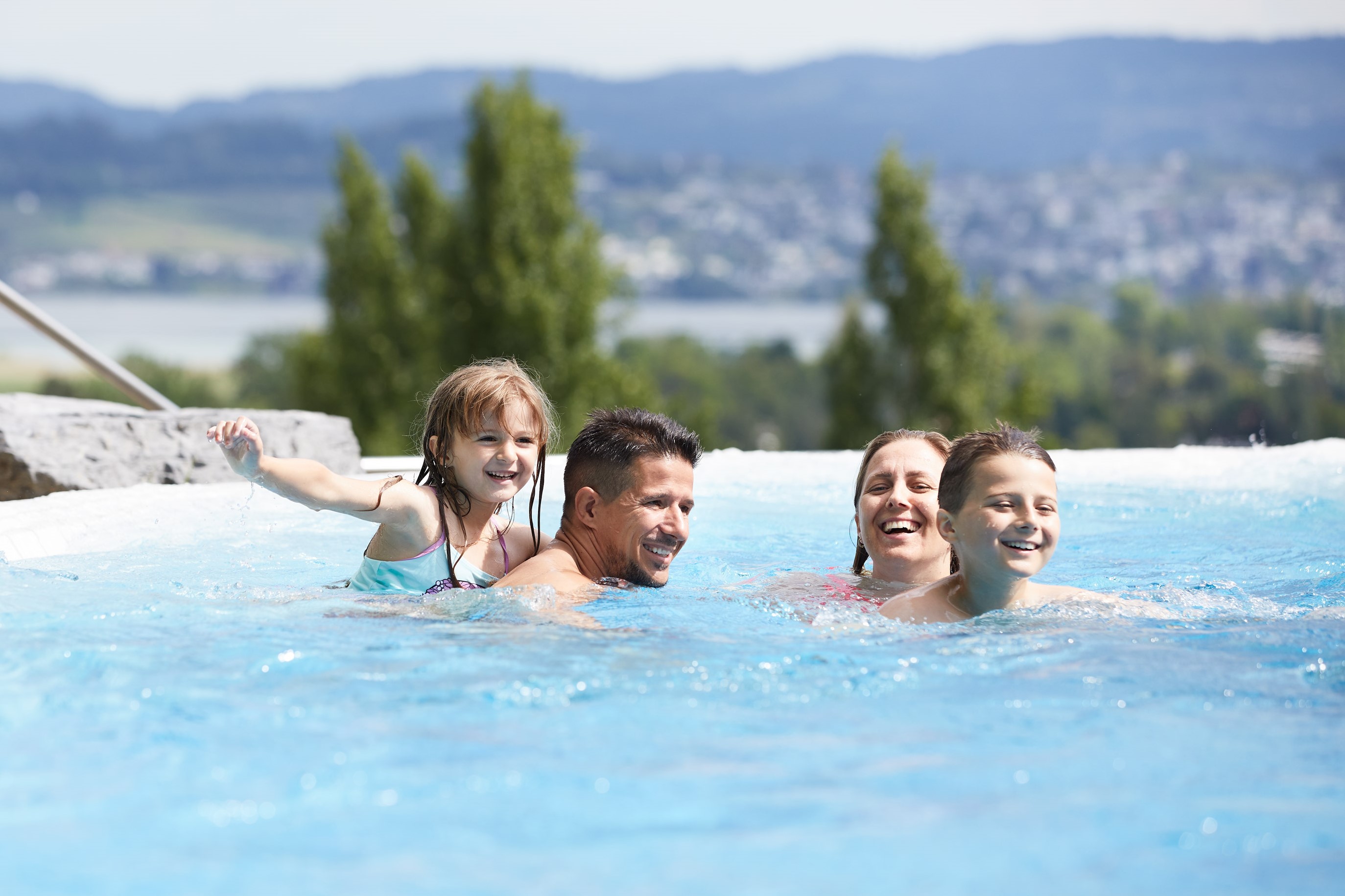 Famille profitant d’une journée ensoleillée à l’Alpamare avec vue sur le lac de Zurich.
