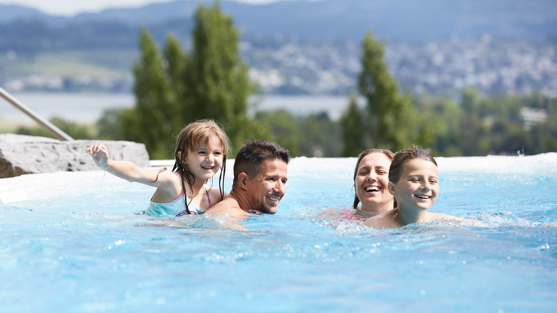 Family enjoying a sunny day at Alpamare with a view of Lake Zurich.