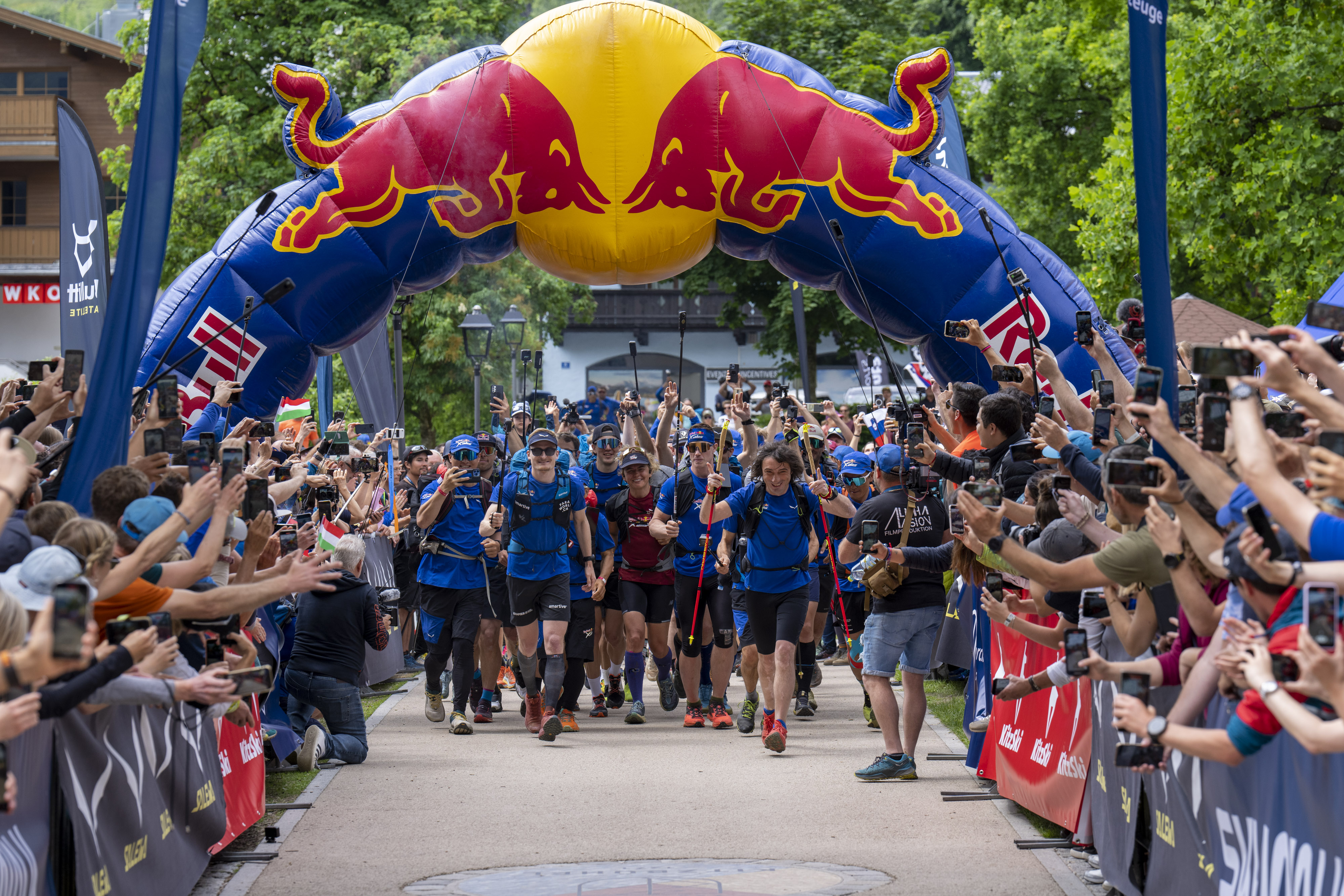 Beaucoup de gens habillés en bleu sous une arche de Redbull. Des côtés, on voit des gens qui applaudissent