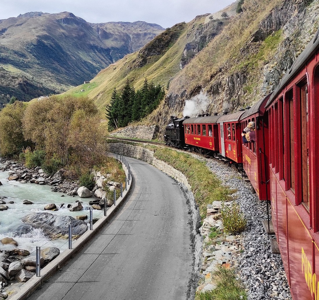 The Furka Steam Railway winds its way along the Reuss River with historic red carriages – an impressive journey through the Alpine landscape between Realp and Oberwald.