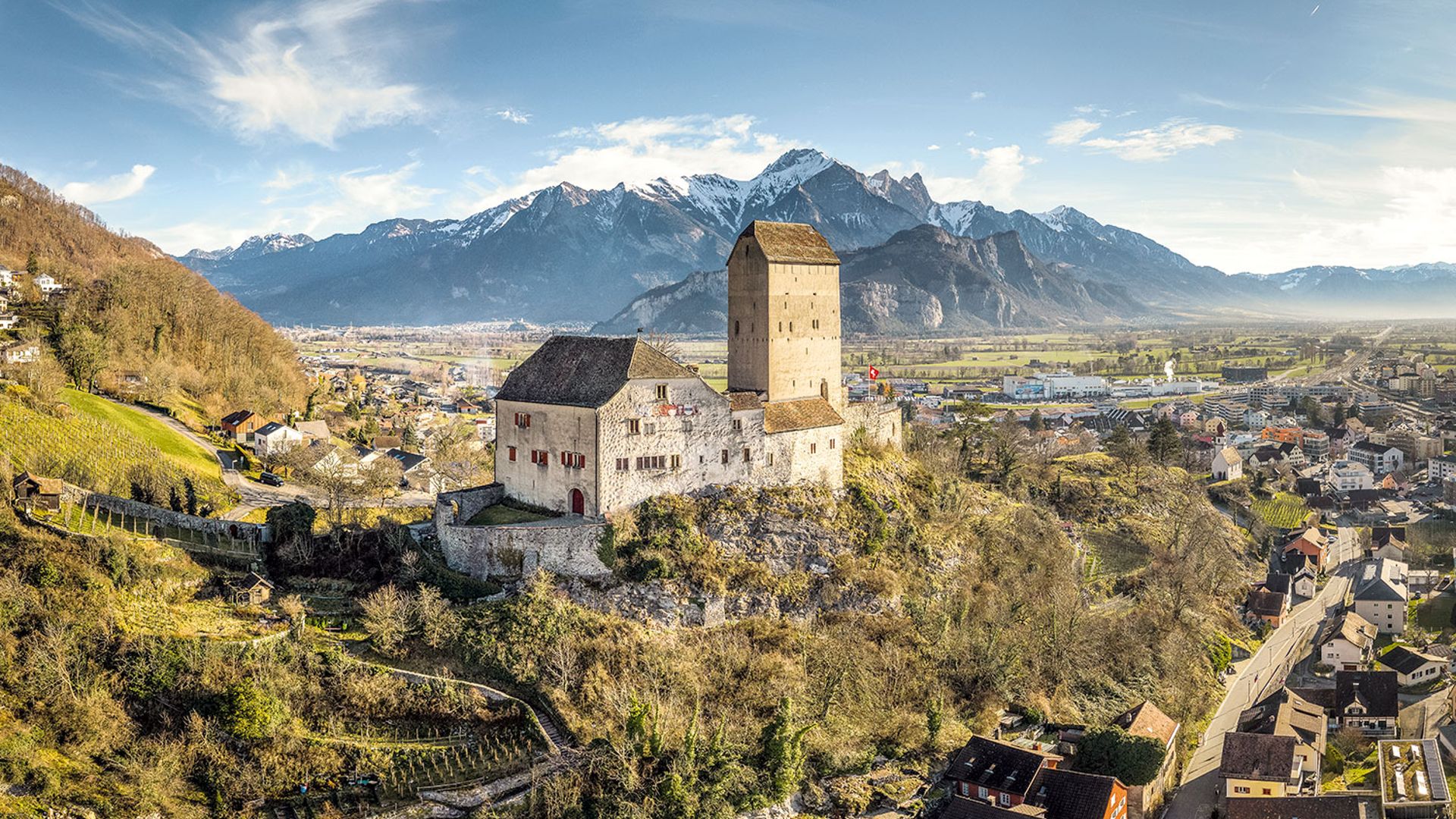 Il castello di Sargans su una collina rocciosa con vista sulla città e sulla valle del Reno, con le montagne innevate sullo sfondo.