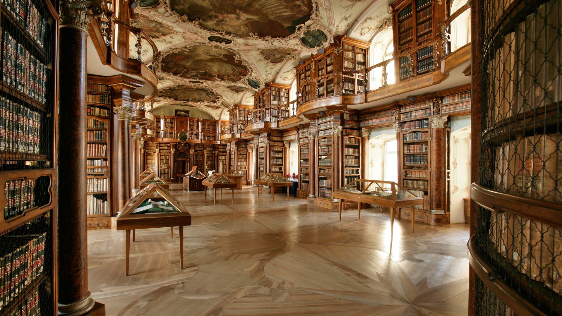 La sala barocca della biblioteca dell’abbazia di San Gallo con affreschi sul soffitto e scaffali storici.