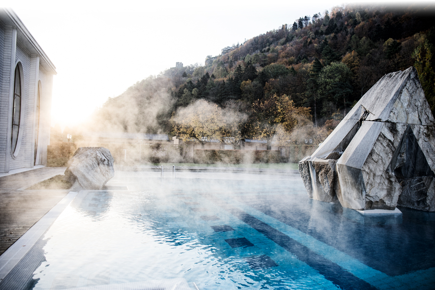 Dampfbadende Tamina Therme in Bad Ragaz mit Blick auf die umliegenden Wälder und Felsen im Morgenlicht.