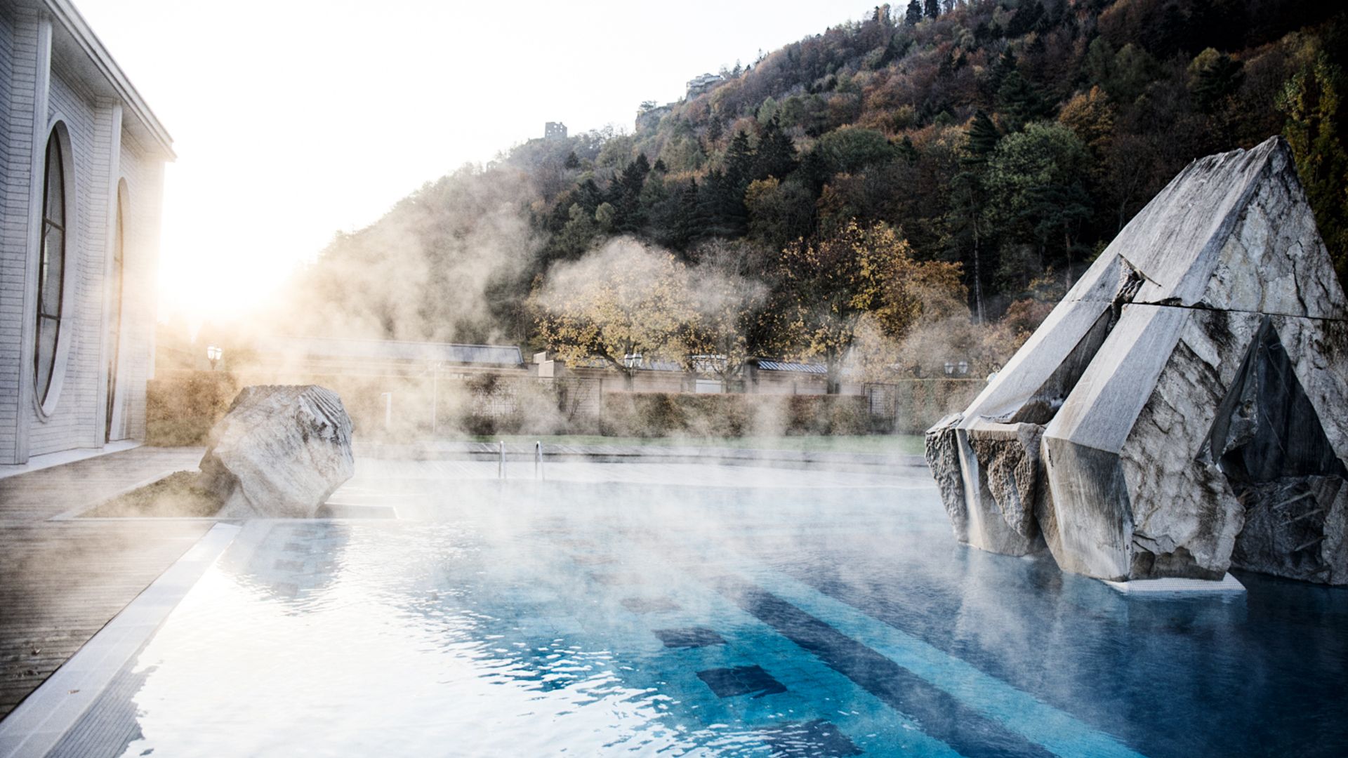 Steaming Tamina Therme spa in Bad Ragaz with surrounding forests and rocks in the morning light.