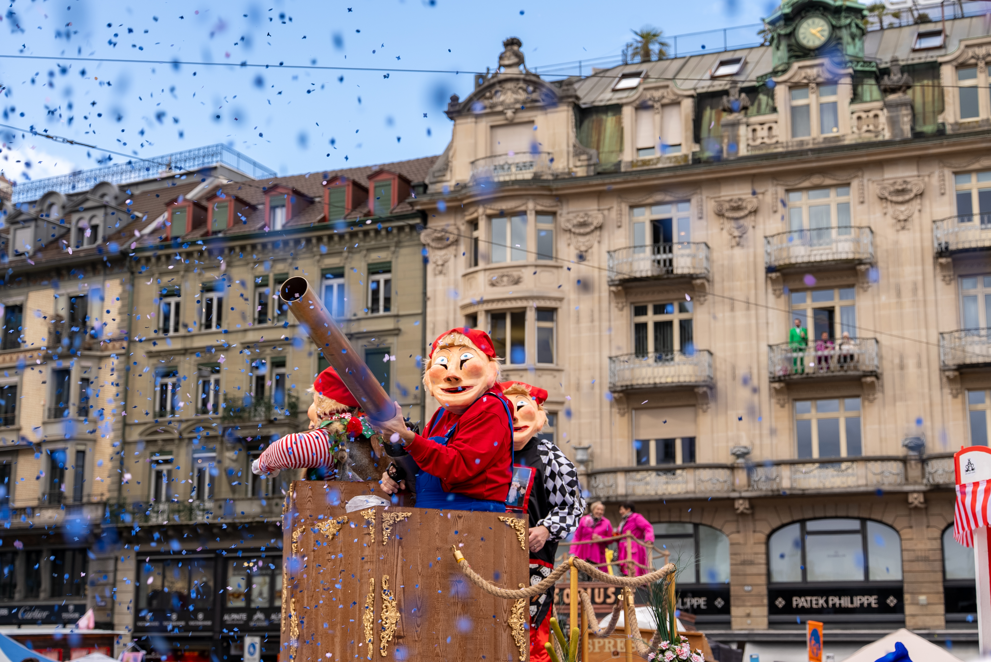 Beim Fasnachtumzug auf der Strassen von Luzern verkleidete Menschen mit einer grossen Konfettibombe.
