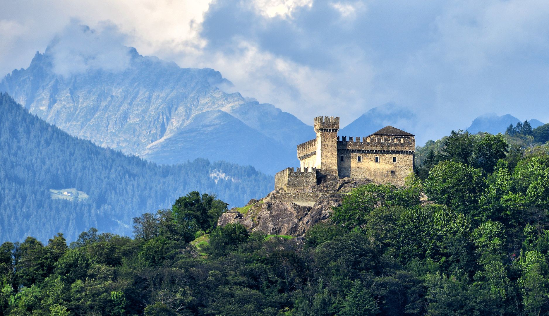 Alte Burg steht auf einem Hügel vor Bergen