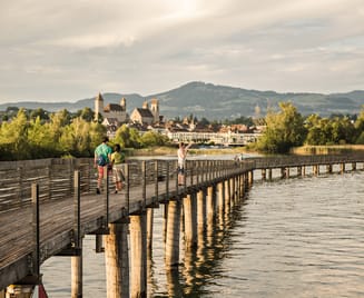 Zwei Personen laufen über den Holzsteg in Rapperswil am See