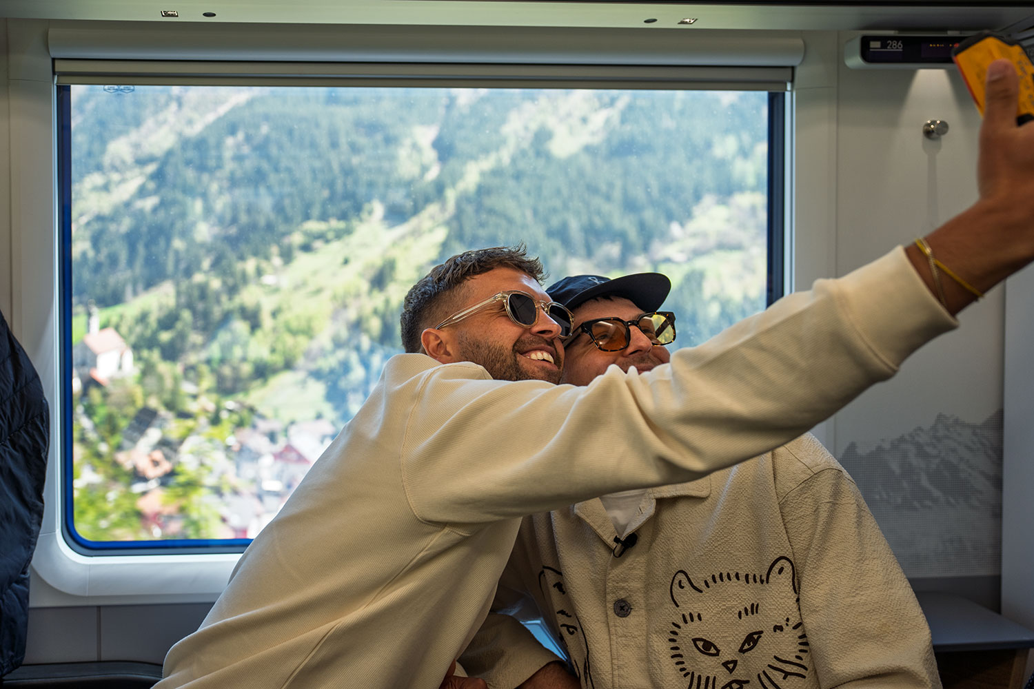 Nico et Noah prennent un selfie à bord du Treno Gottardo, avec l’église de Wassen visible par la fenêtre en arrière-plan.