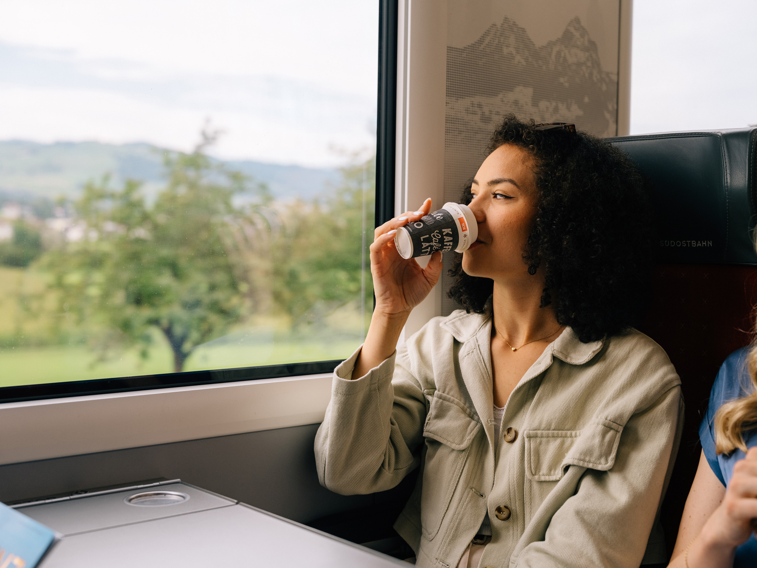 Une jeune femme savoure un café au bistrot du train de la Südostbahn
