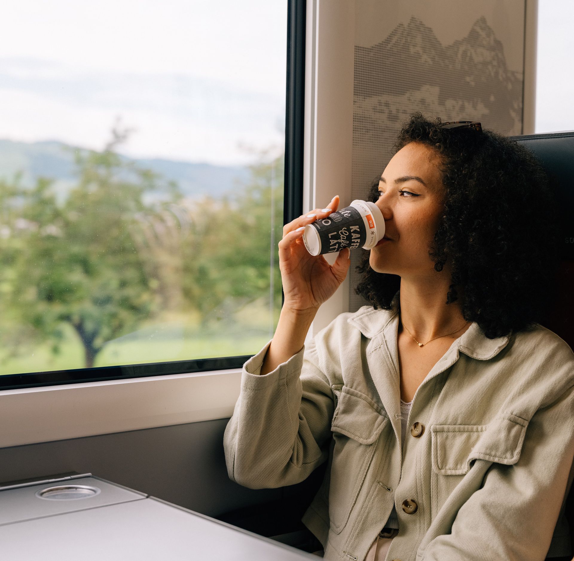 Une jeune femme savoure un café au bistrot du train de la Südostbahn