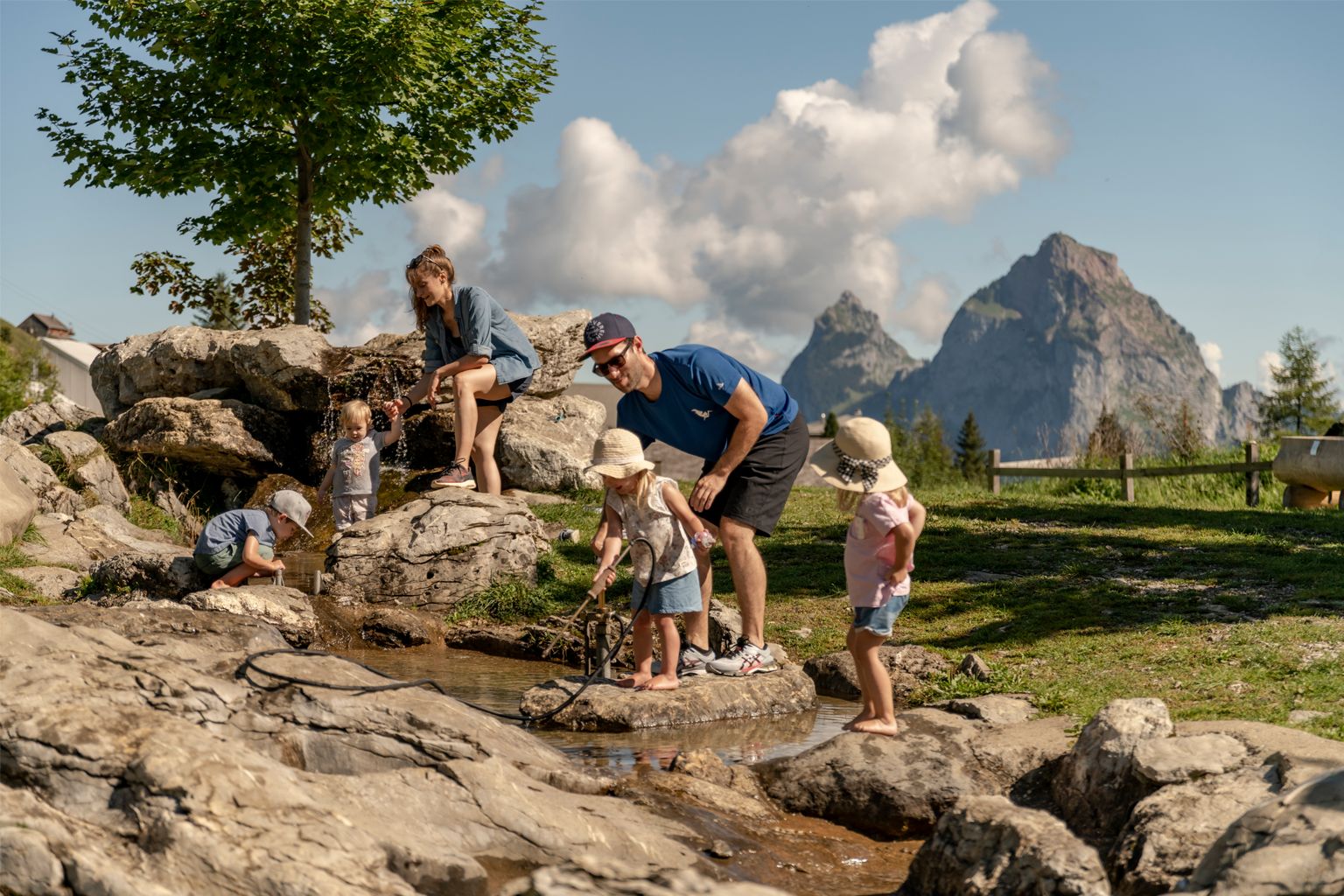 Familie spielt am Wasser eines kleinen Flusses in den Bergen