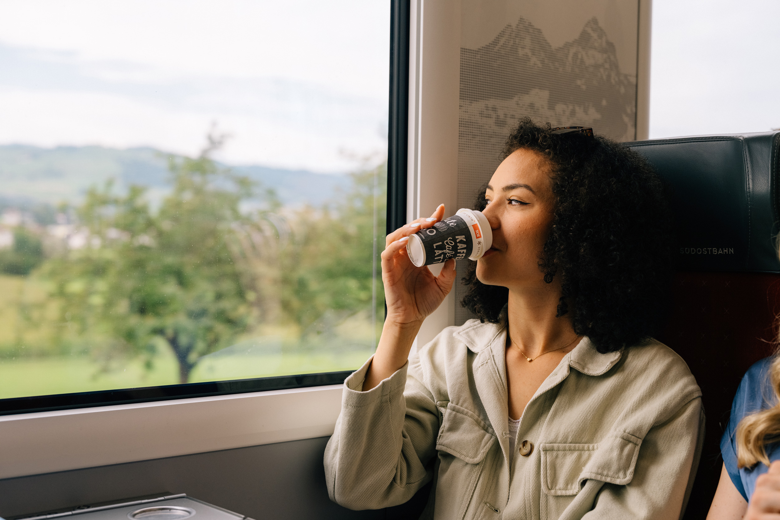 Une jeune femme savoure un café au bistrot du train de la Südostbahn