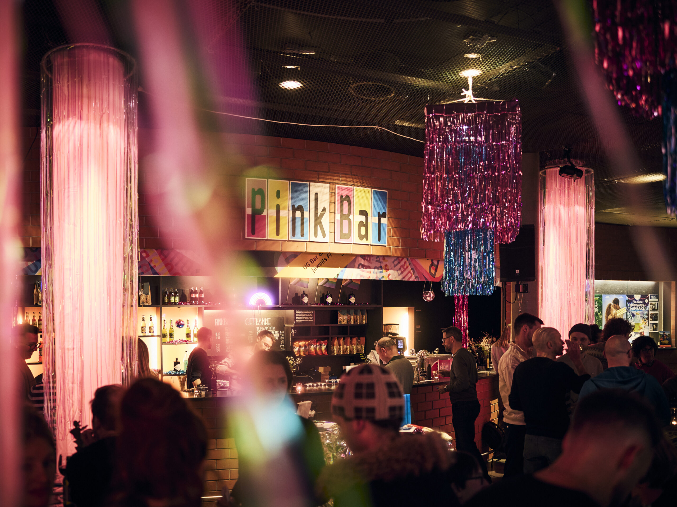 Feststimmung in einer Bar. Alles Pink dekoriert mit vielen Menschen drinn.   