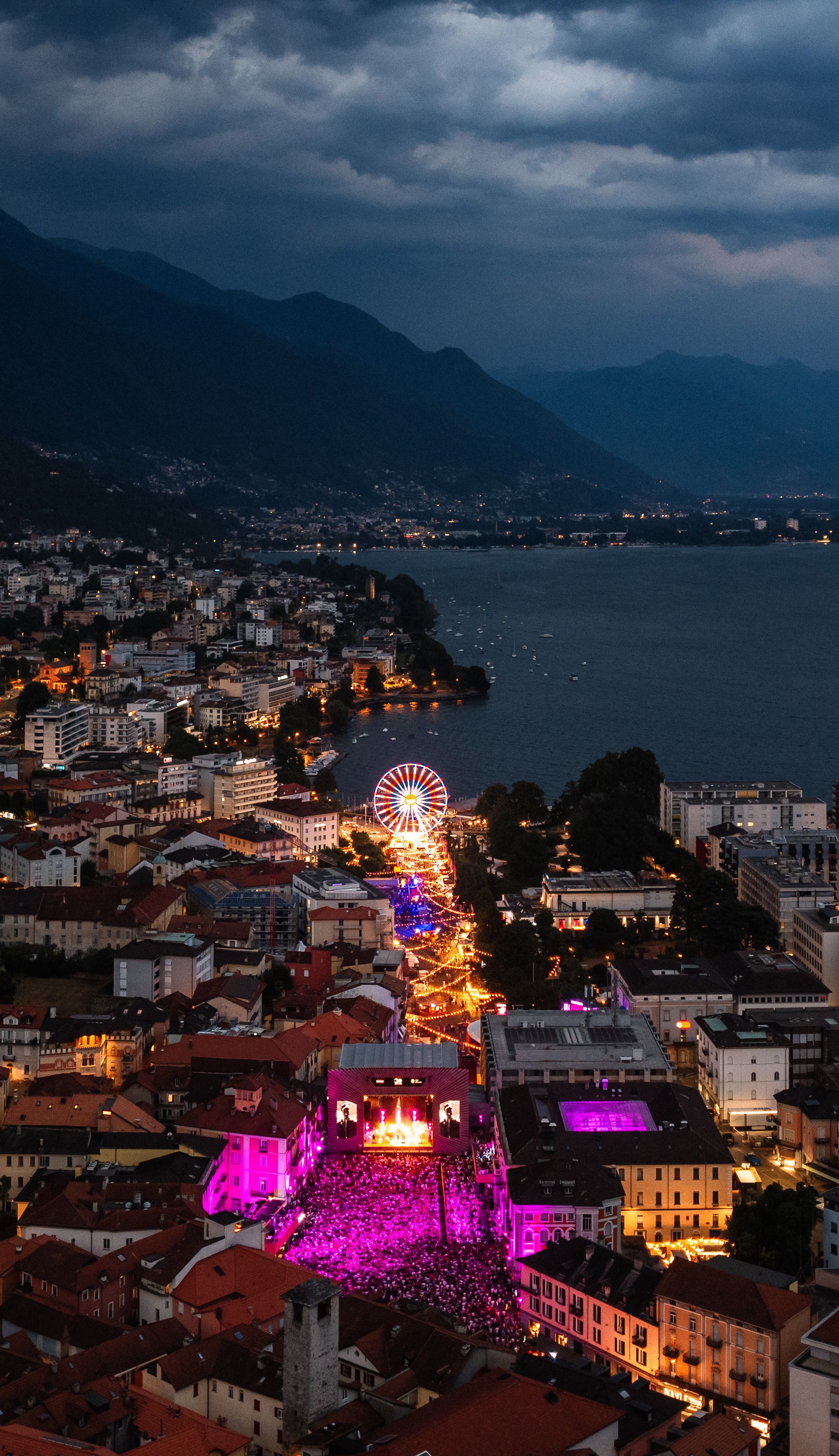 Night aerial view of Locarno with illuminated Moon+Stars festival area, Ferris wheel and Lake Maggiore