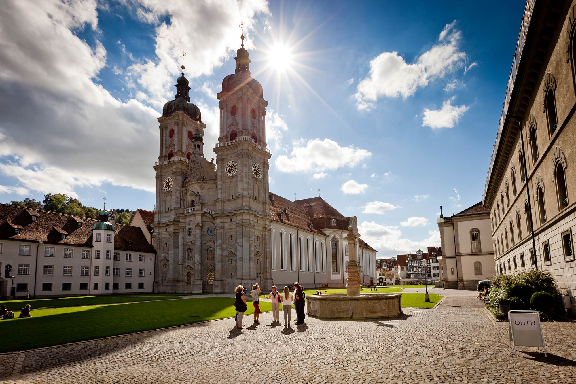 Stiftskirche St. Gallen im Sonnenlicht mit Besucherinnen und Besuchern auf dem Klosterplatz.