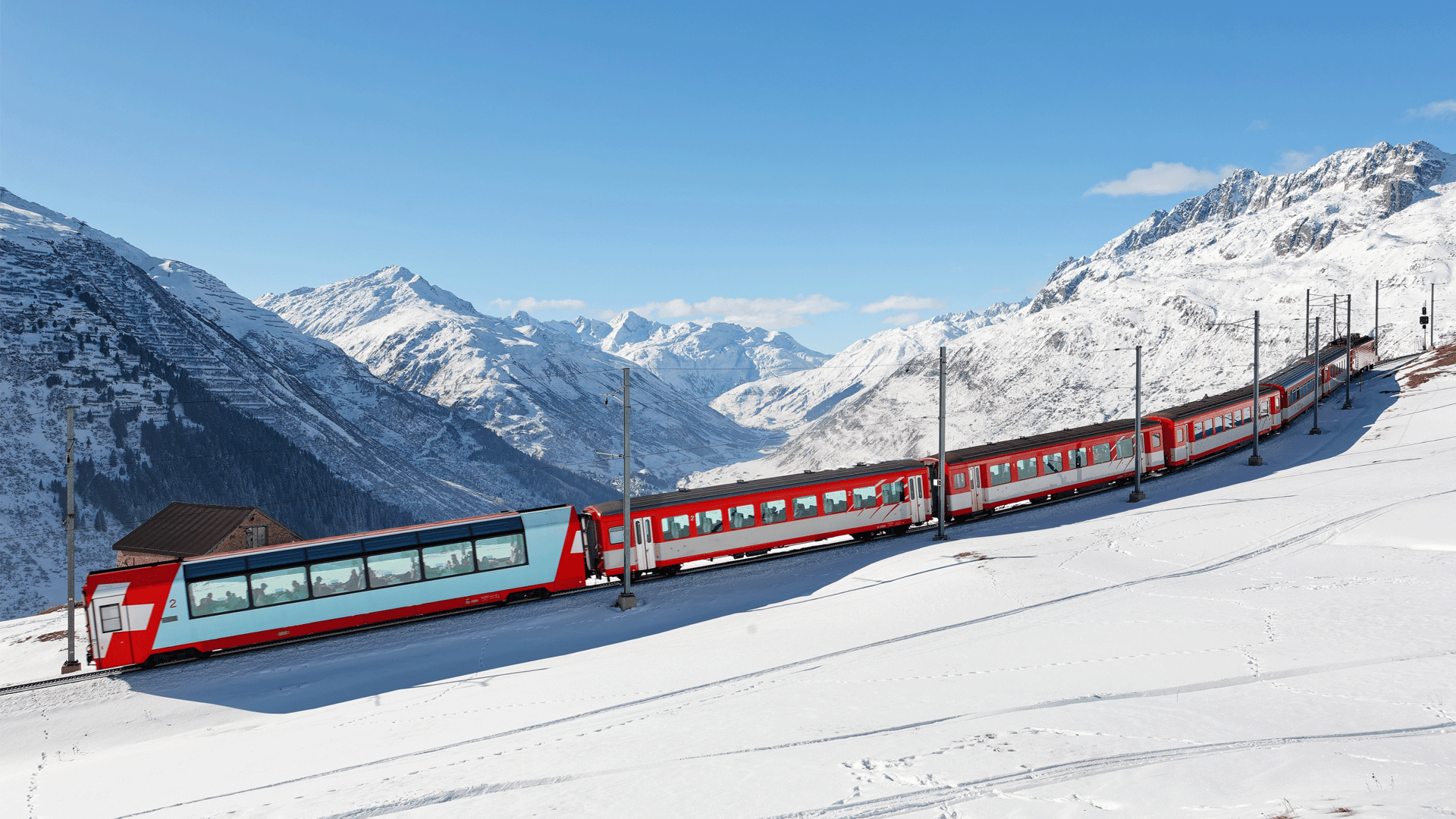 rot weisser Zug fährt durch schneebedeckte Berglandschaft