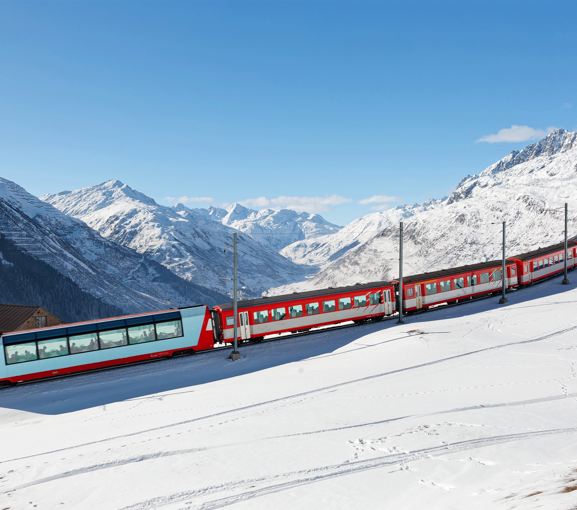 rot weisser Zug fährt durch schneebedeckte Berglandschaft