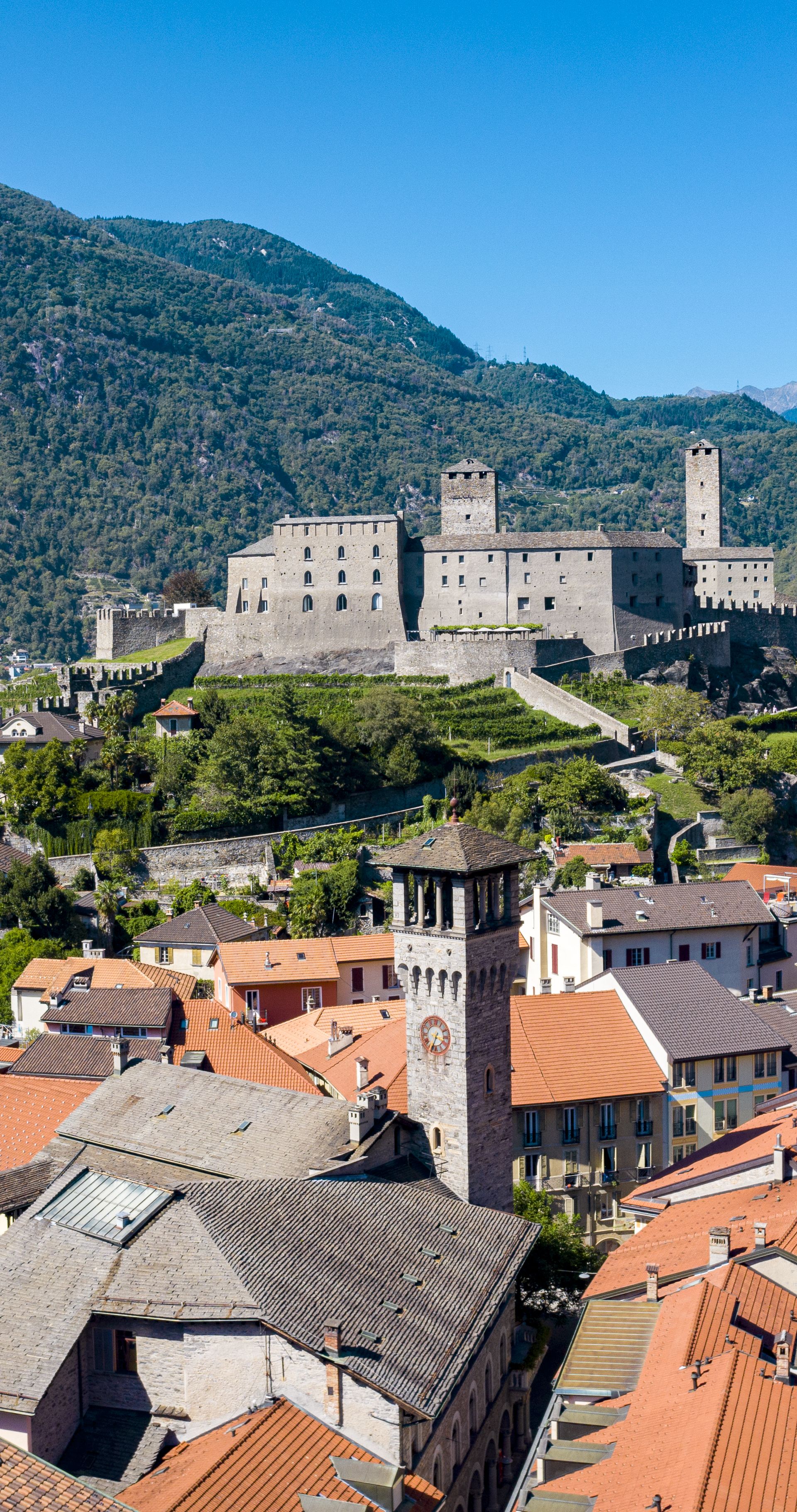 Vue aérienne de Bellinzona avec le majestueux Castelgrande, entouré des toits rouges de la vieille ville et des montagnes verdoyantes du Tessin.