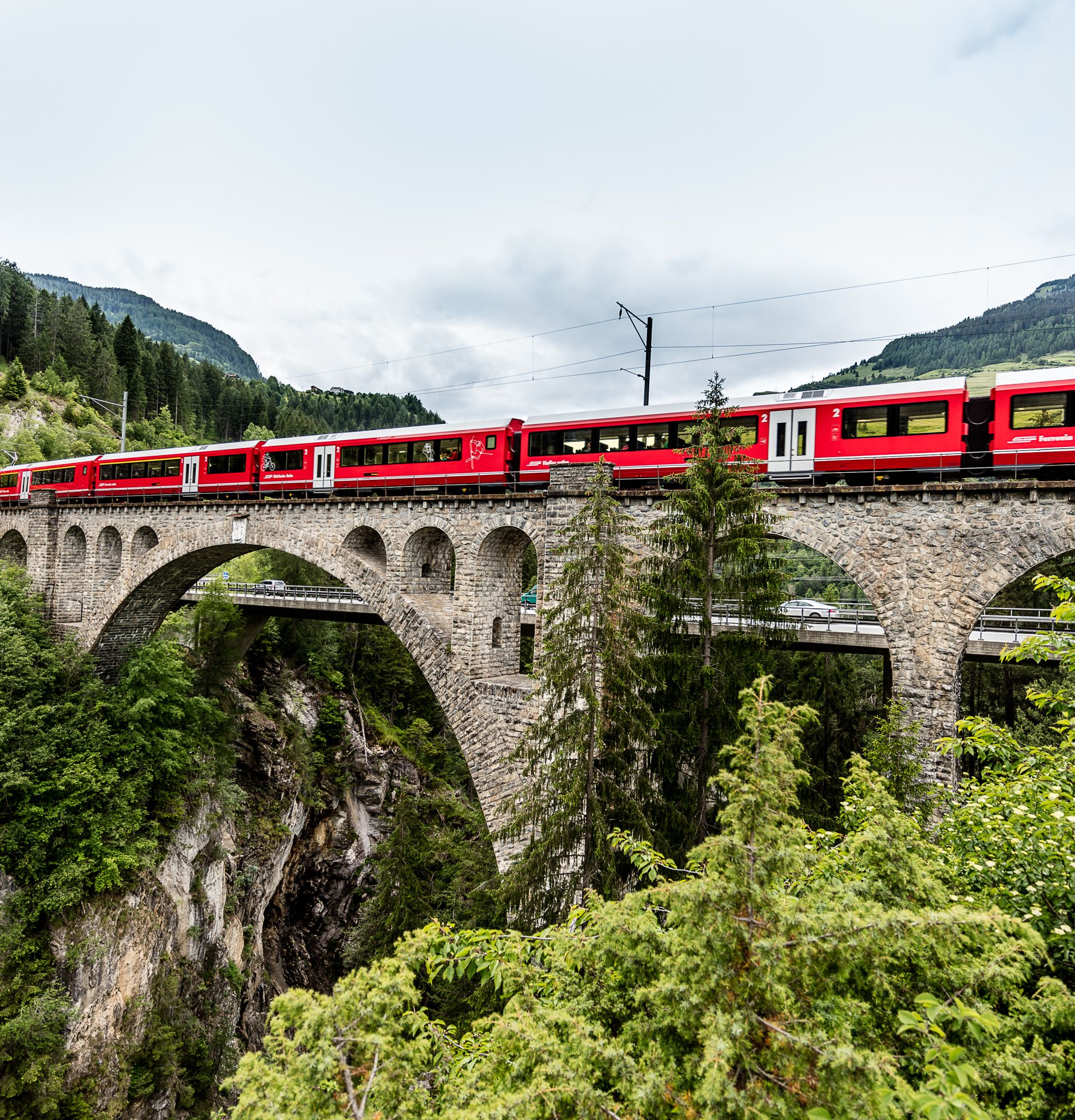 Un train rouge passe sur un viaduc