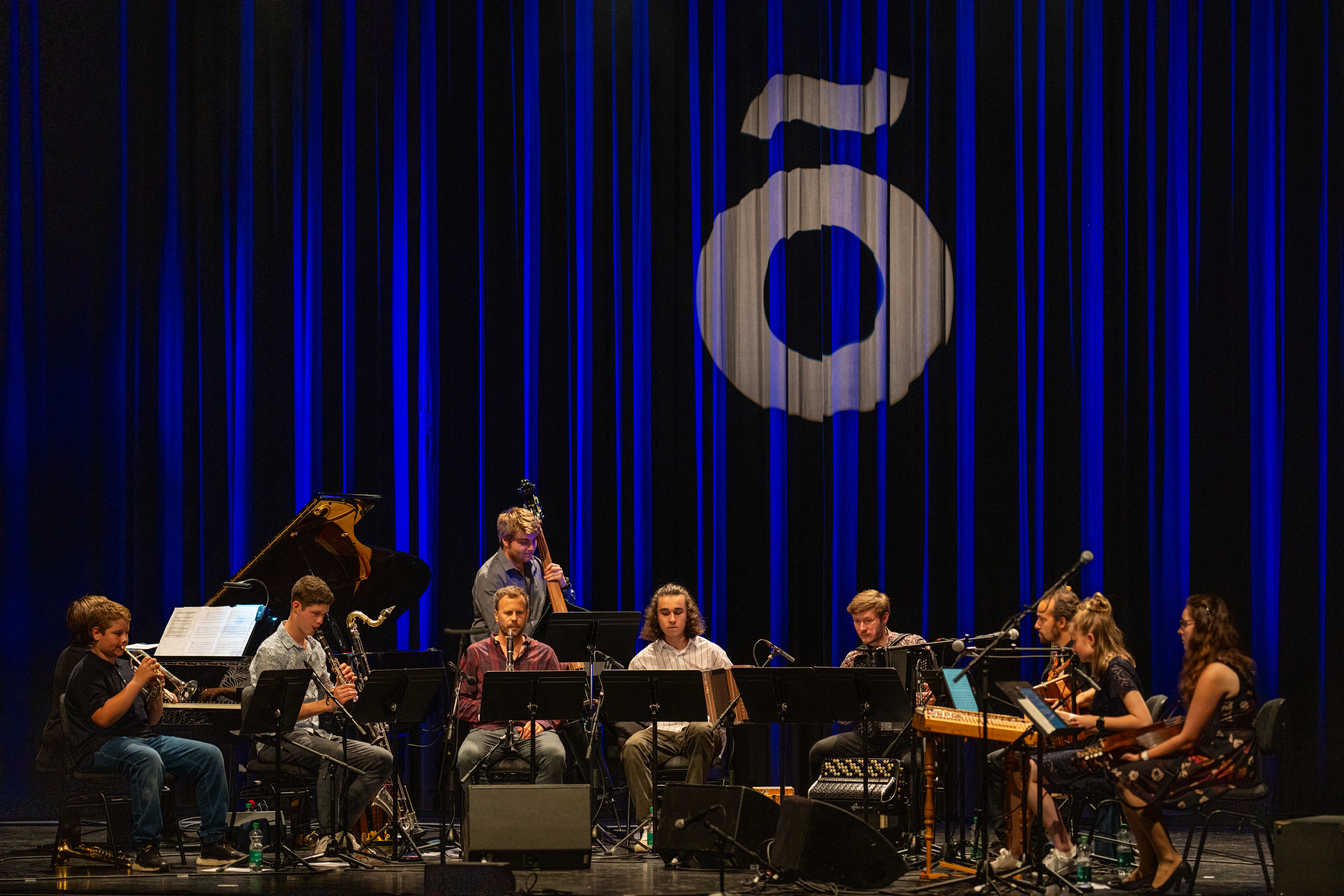 Un'orchestra davanti a un sipario blu.