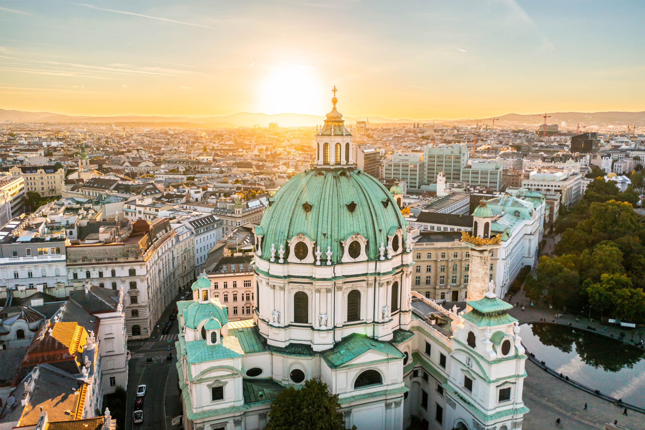 Kirche mit Dom im Vordergrund einer Stadt während die Sonne untergeht