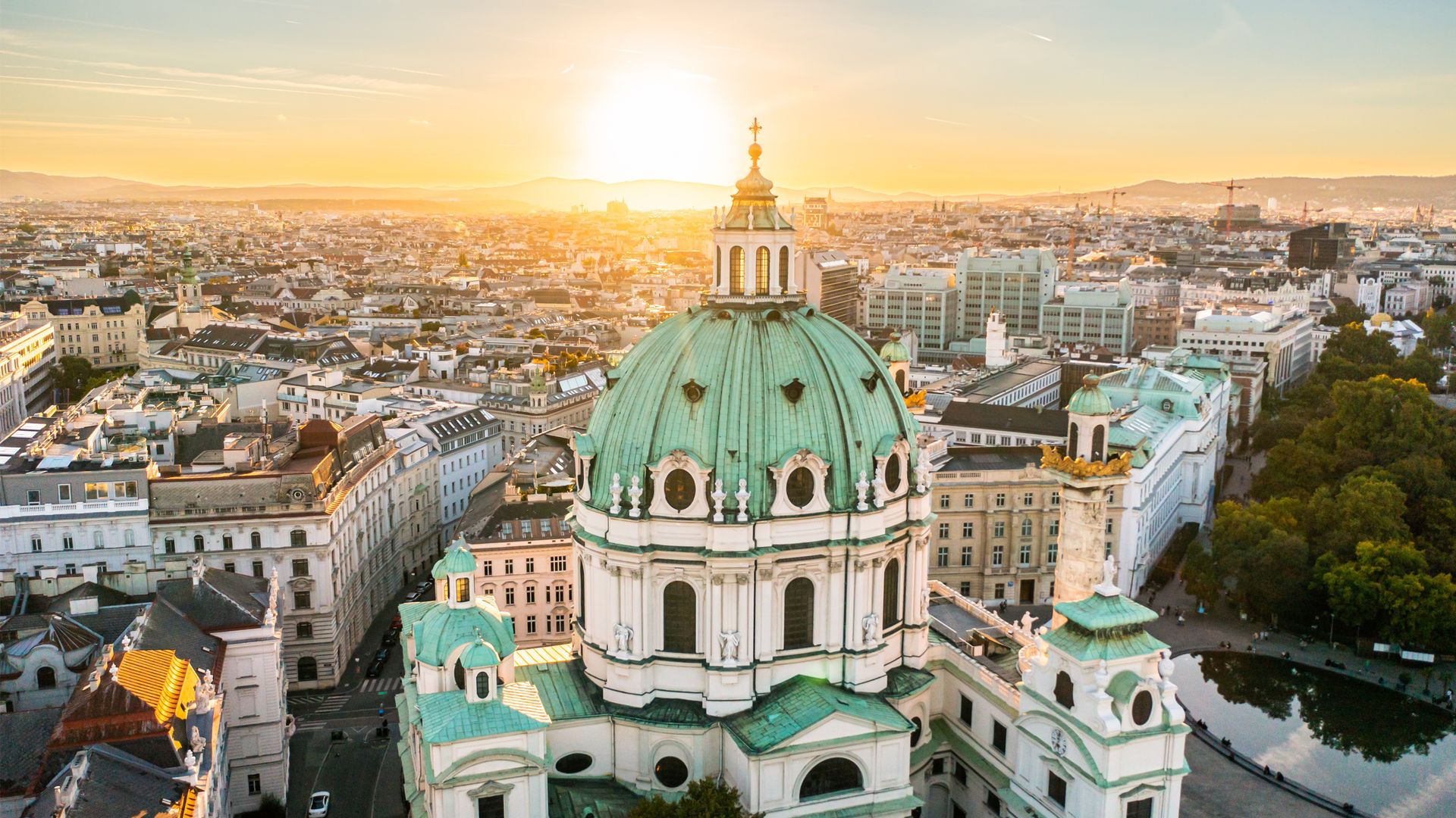 Kirche mit Dom im Vordergrund einer Stadt während die Sonne untergeht