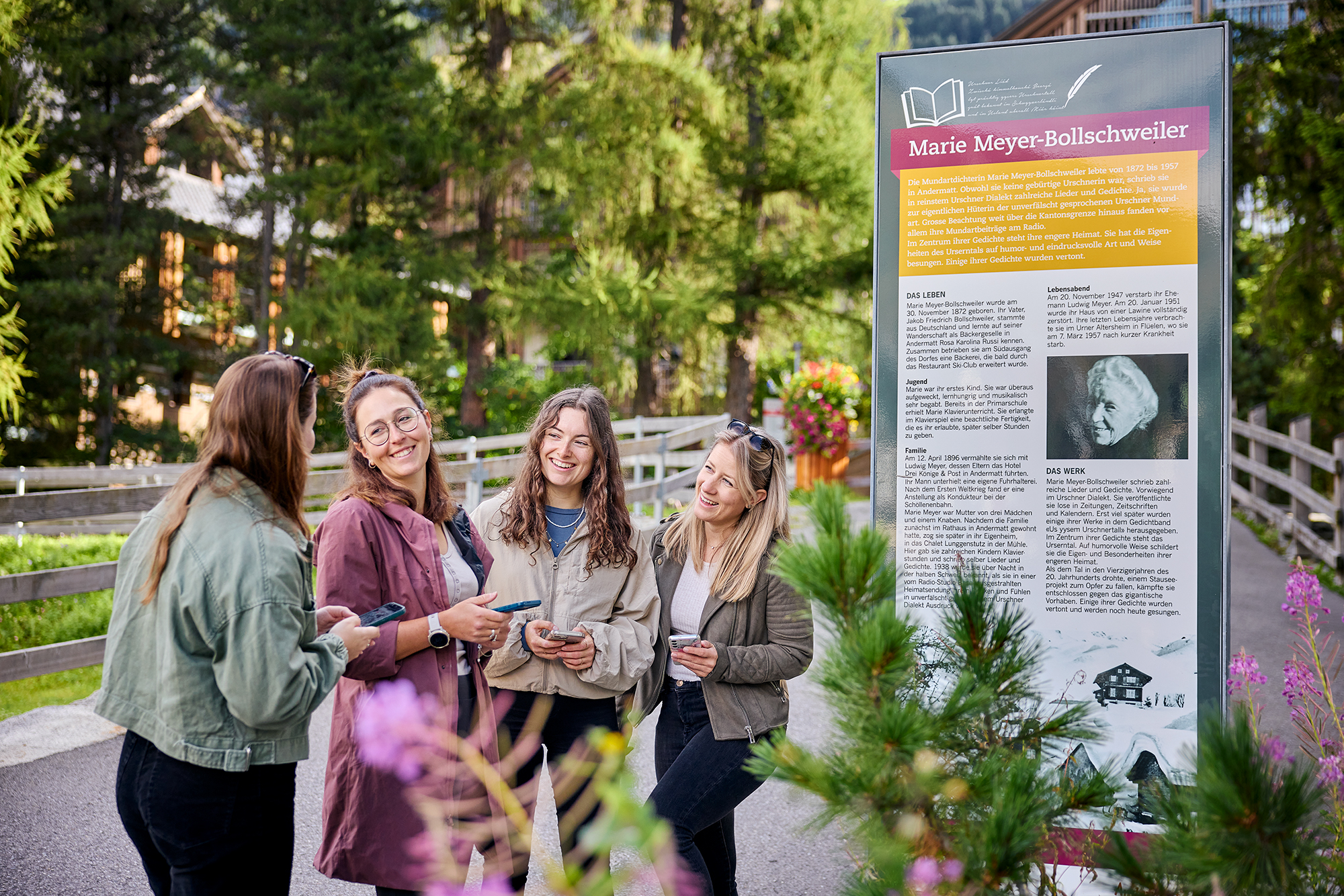 4 Frauen studieren eine Broschüre auf einem Spazierweg bei einem Informationsschild