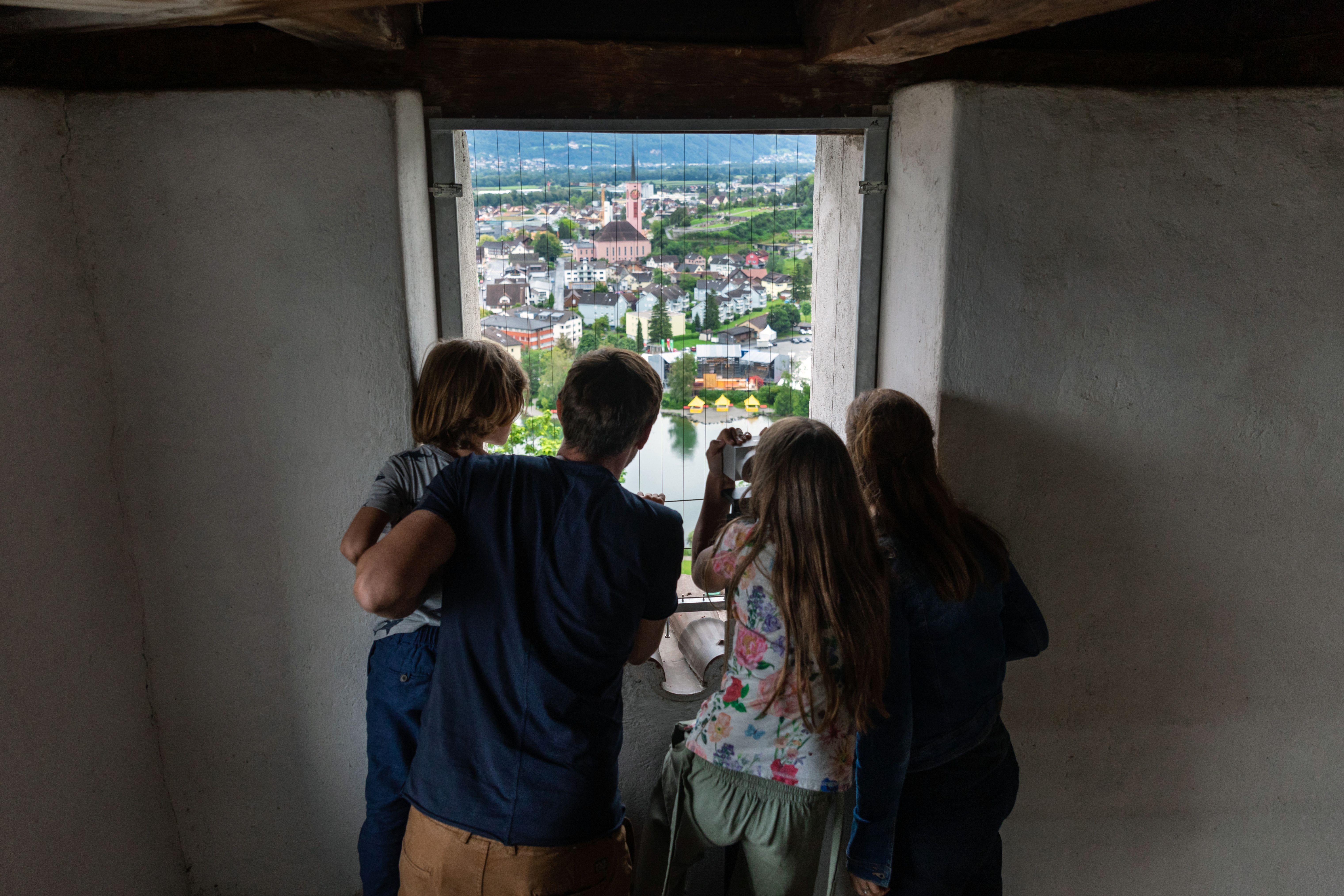 Vierköpfige Familie schaut hinaus auf das Städtchen mit Kirche und Teich