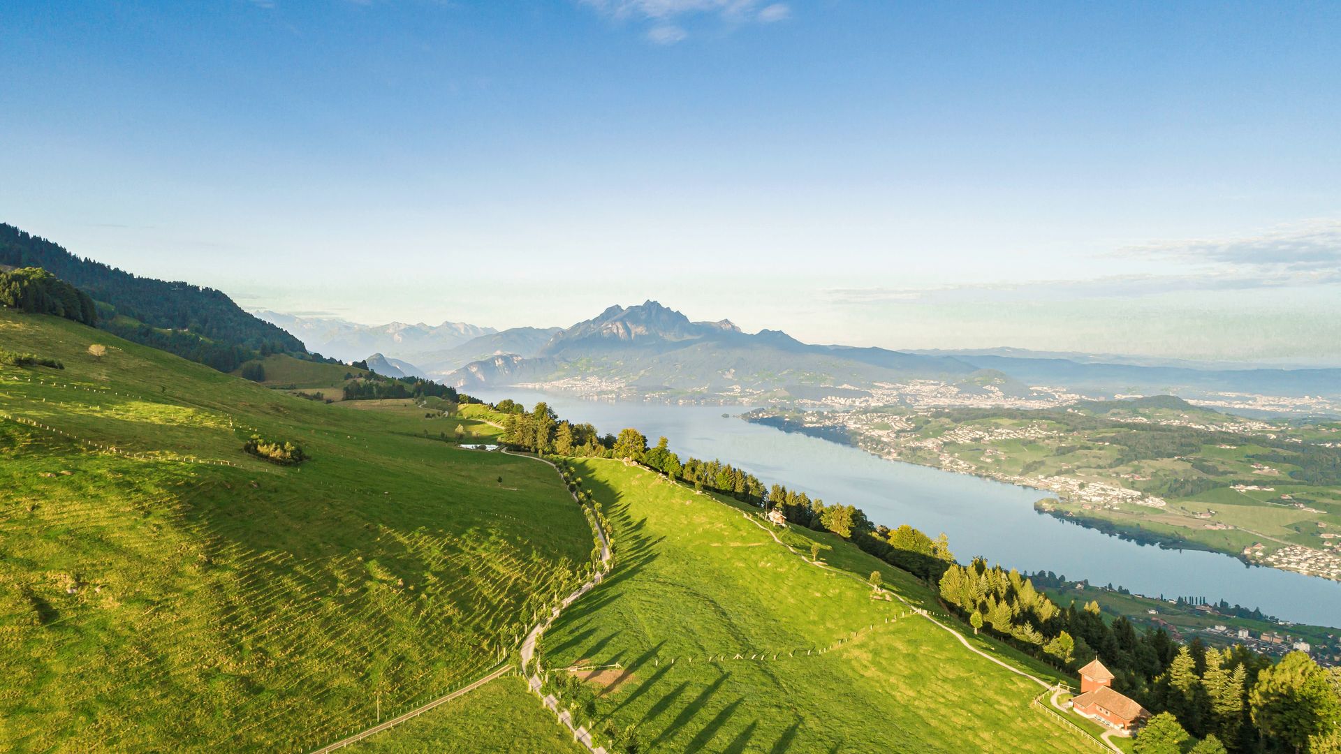 Summer view from Seebodenalp above Küssnacht am Rigi overlooking Lake Lucerne and Mount Pilatus, with rolling green meadows and clear mountain light.