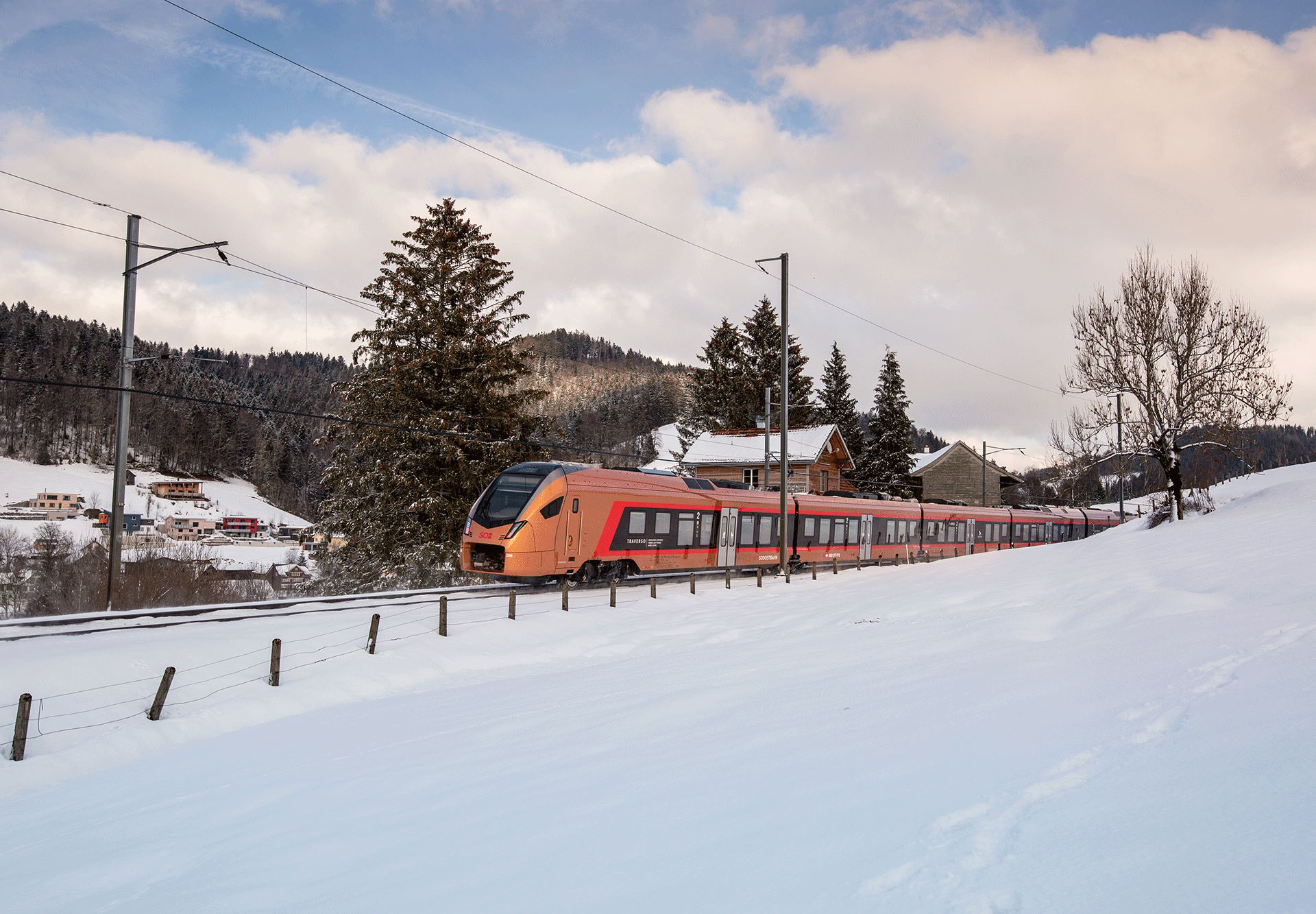 Kupferfarbener Zug fährt durch Winterlandschaft
