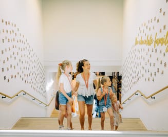 Mutter mit drei Kindern läuft Treppe in Museum hoch