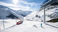 Mittelstation Nätschen im Winter mit dem Gütsch-Express und der Matterhorn Gotthard Bahn im Vordergrund und Aussicht ins Urserntal