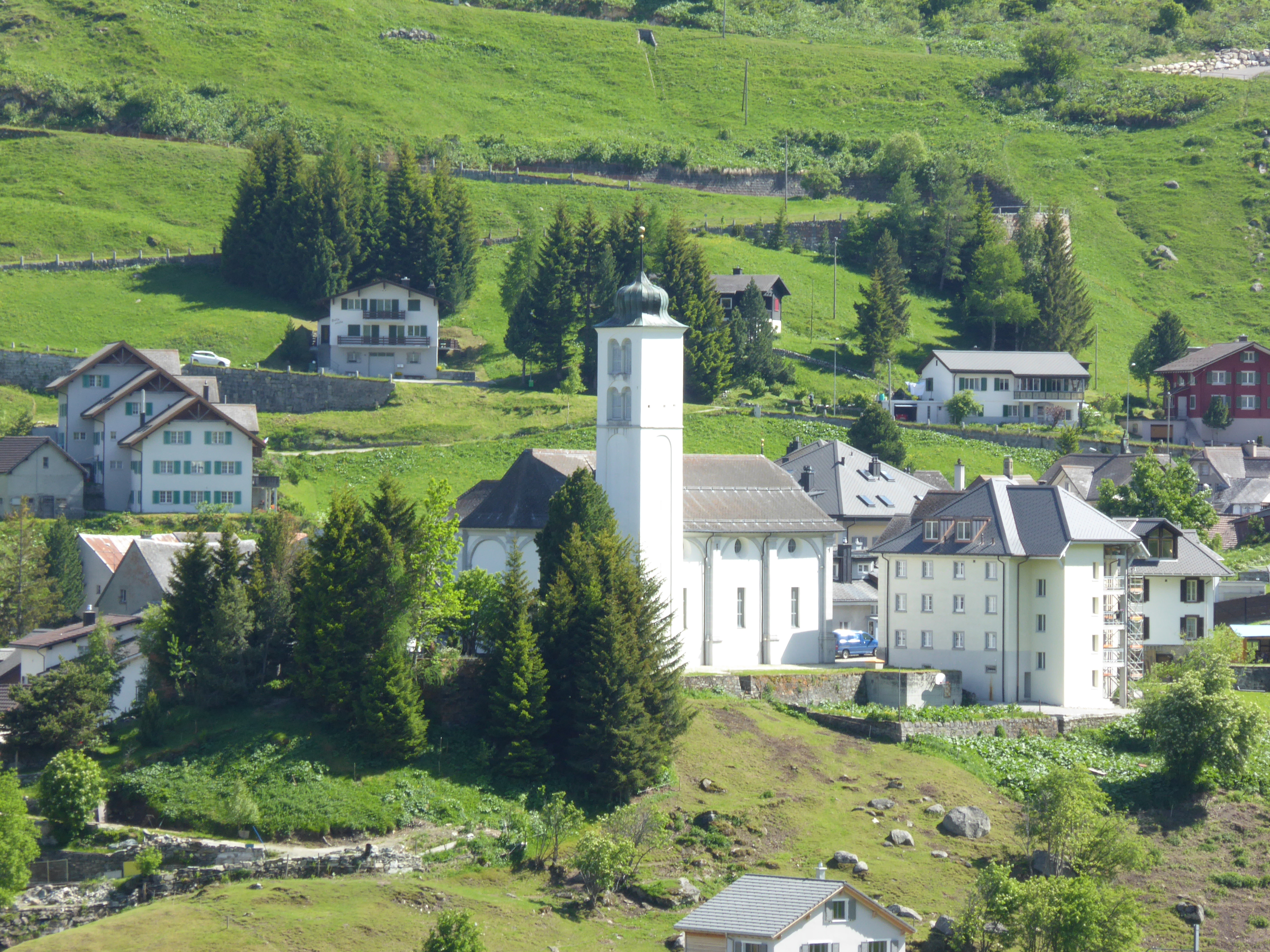 Parish church Maria Himmelfahrt with distinctive tower in a green mountain village surrounded by houses