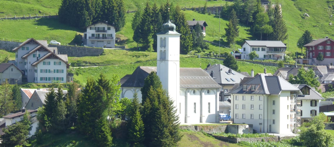 Chiesa parrocchiale Maria Himmelfahrt con torre distintiva in un villaggio di montagna verde circondato da case
