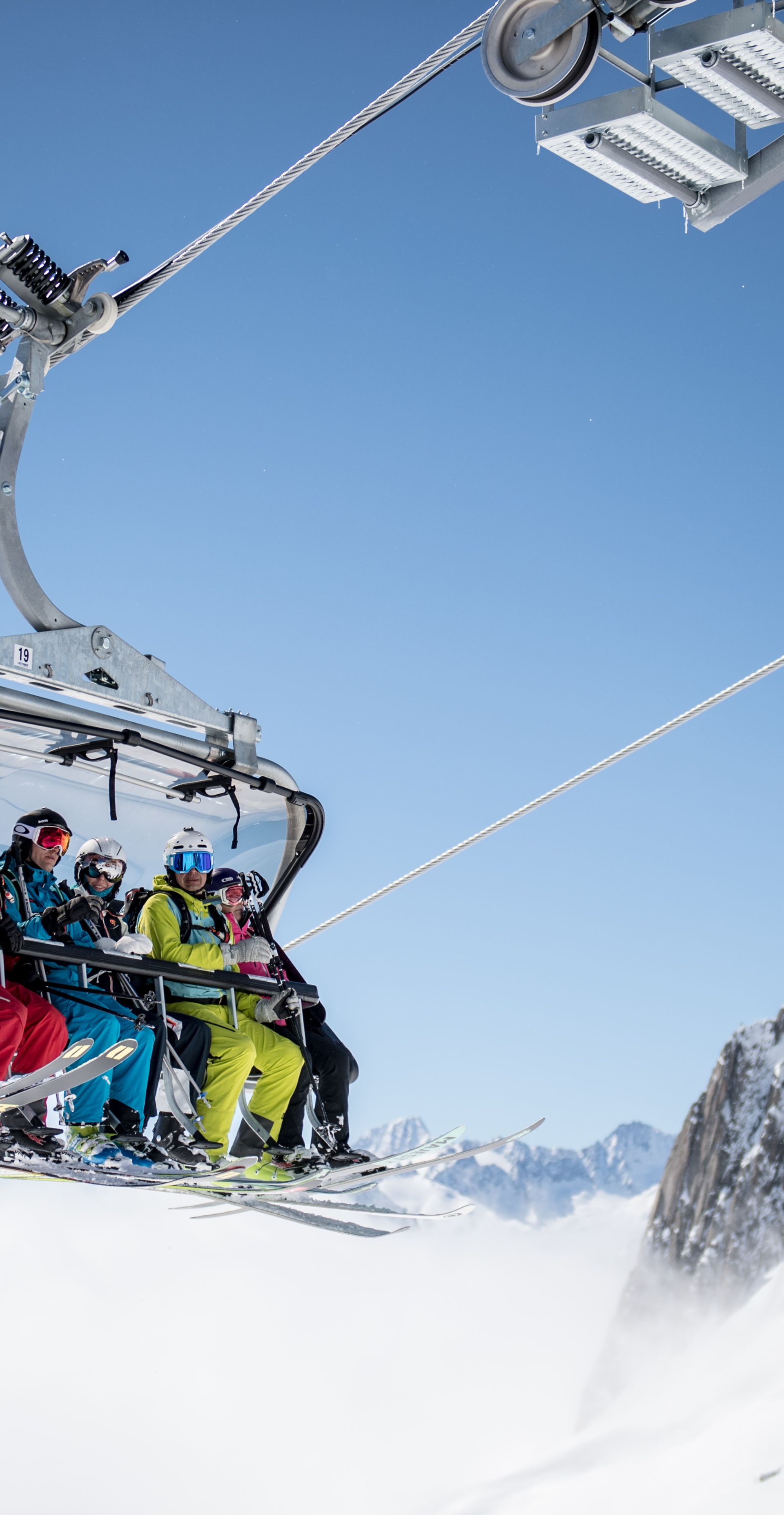 Sesselbahn mit sechs Wintersportlerinnen und -sportler über den Wolken unterwegs in Richtung Schneehüenerstock