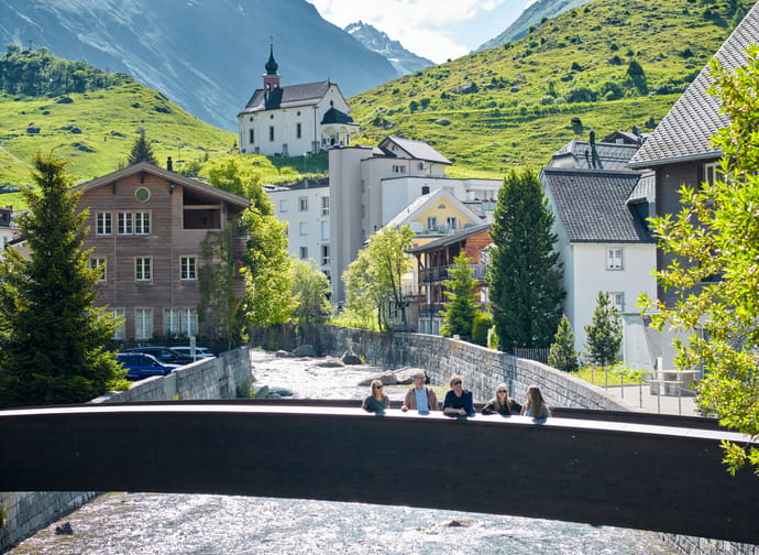 Dorfführung auf Brücke mit Kapelle im Hintergrund