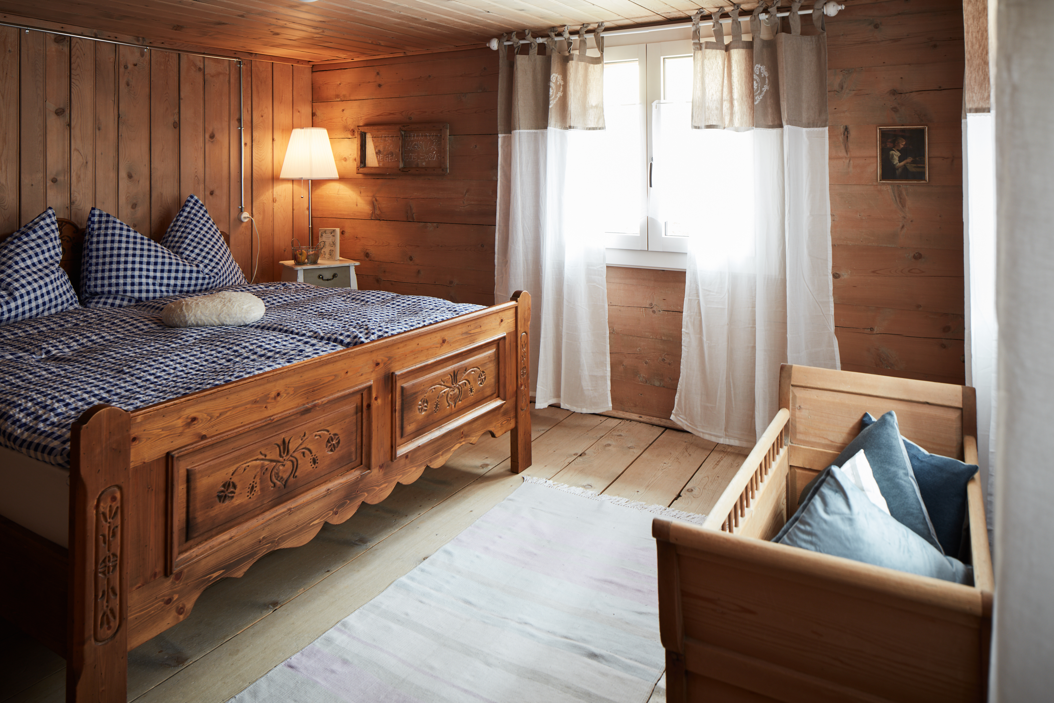 In dem Bild ist ein Schlafzimmer mit einem Doppelbett und einem Babybett zu sehen. 