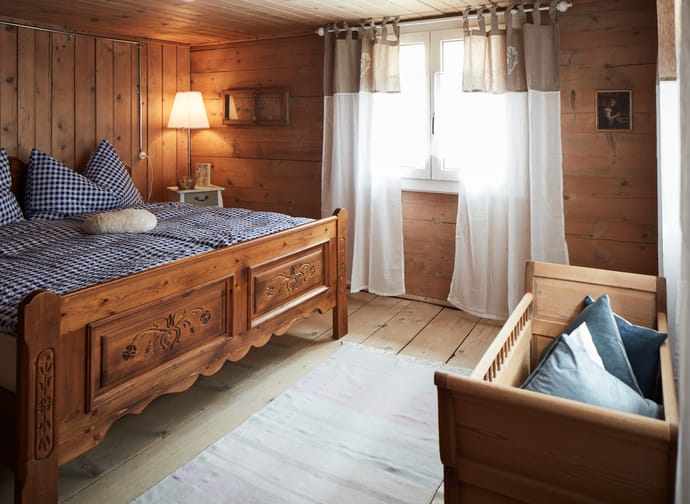 In dem Bild ist ein Schlafzimmer mit einem Doppelbett und einem Babybett zu sehen.