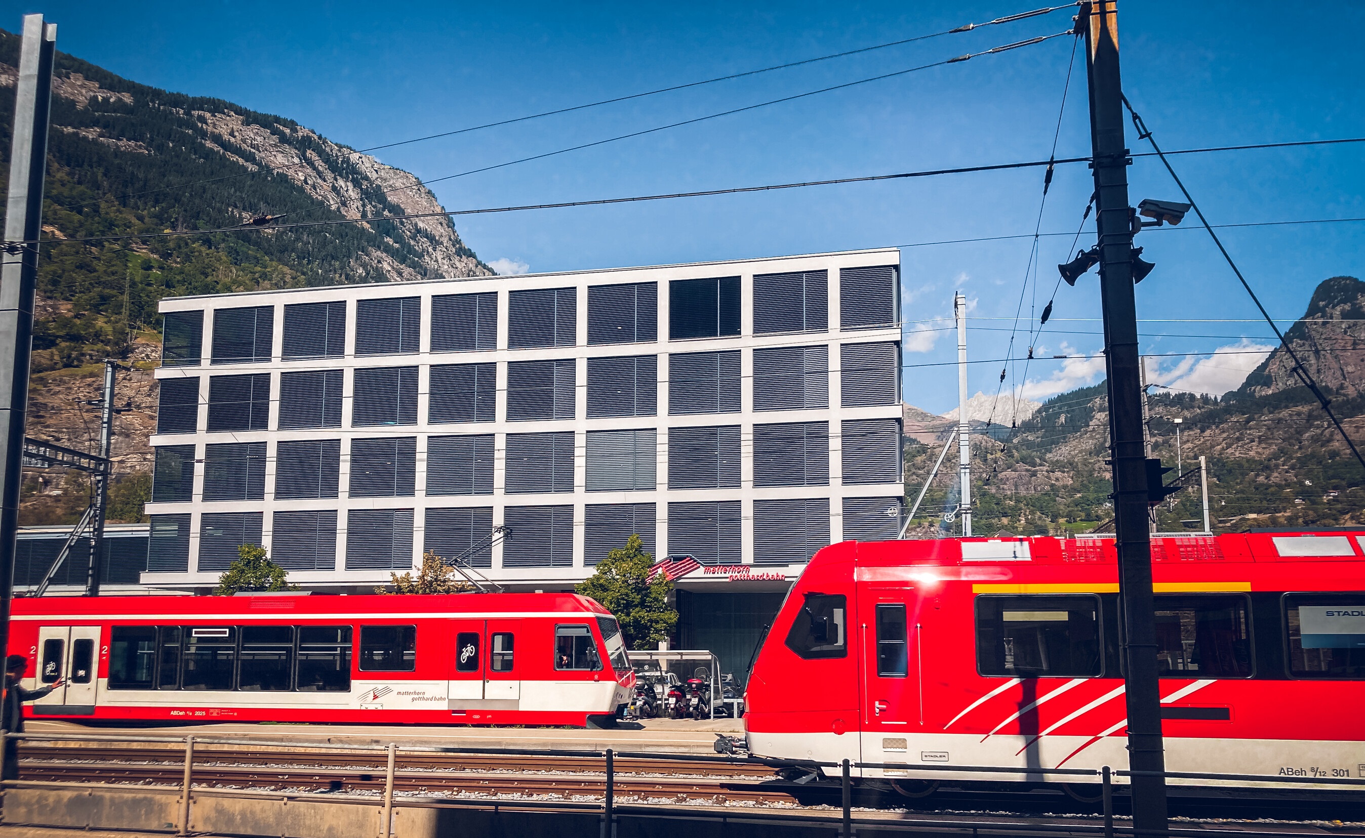 Die Matterhorn Gotthard Bahn in Brig, vor den Büros des Eisenbahnunternehmens, an einem sonnigen Tag.