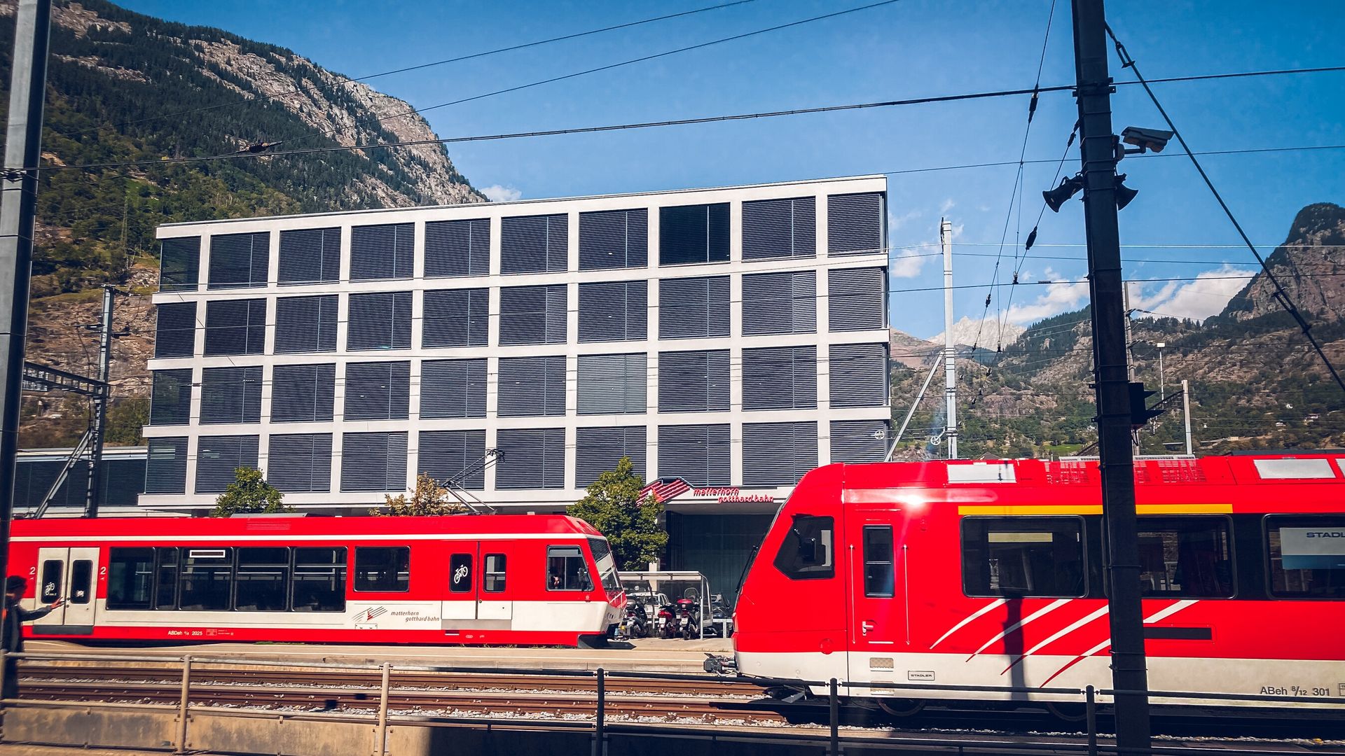 Die Matterhorn Gotthard Bahn in Brig, vor den Büros des Eisenbahnunternehmens, an einem sonnigen Tag.
