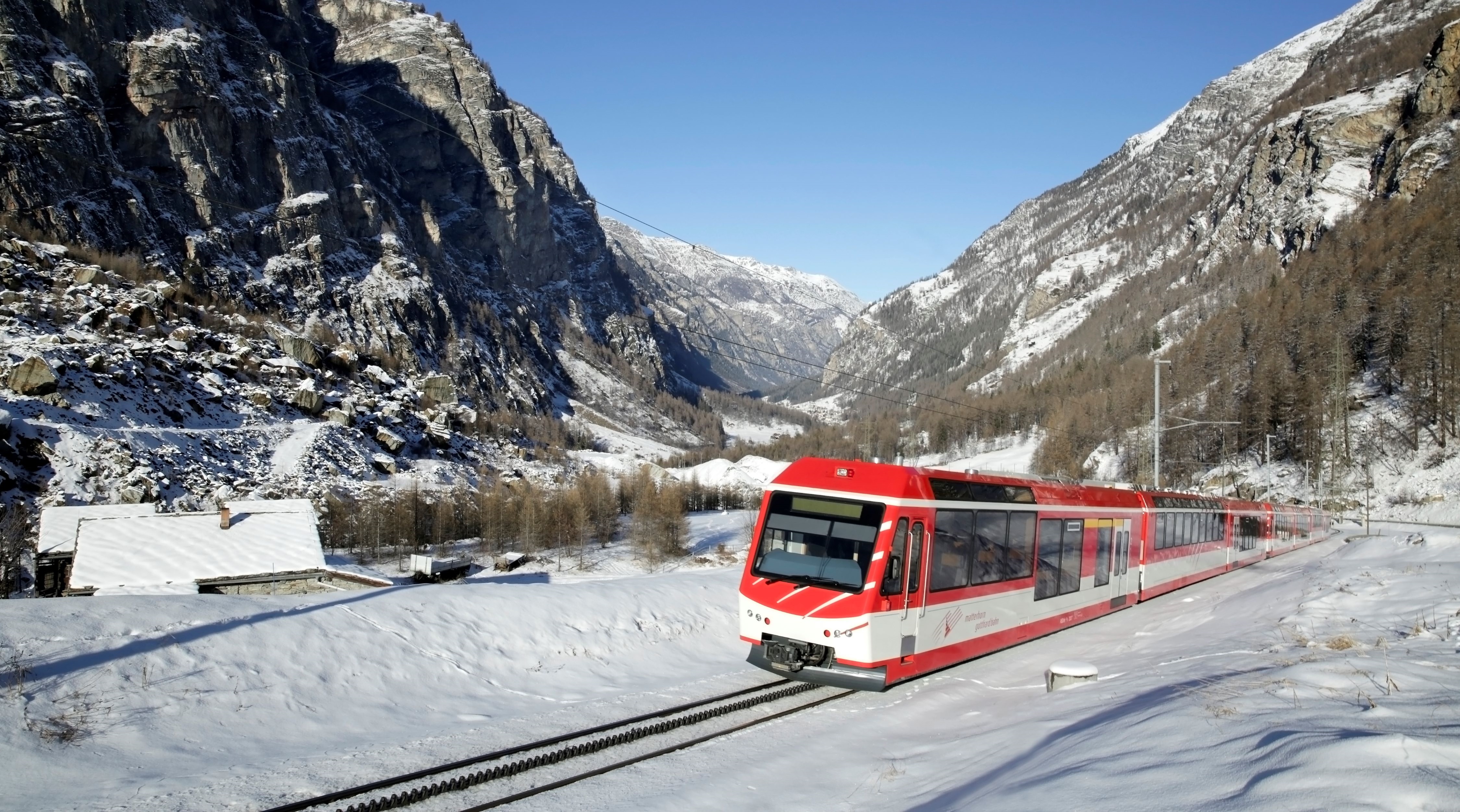Die Matterhorn Gotthard Bahn fährt in Richtung Zermatt und durchquert dabei die Gemeinde Randa, während die Landschaft mit Schnee bedeckt ist. 