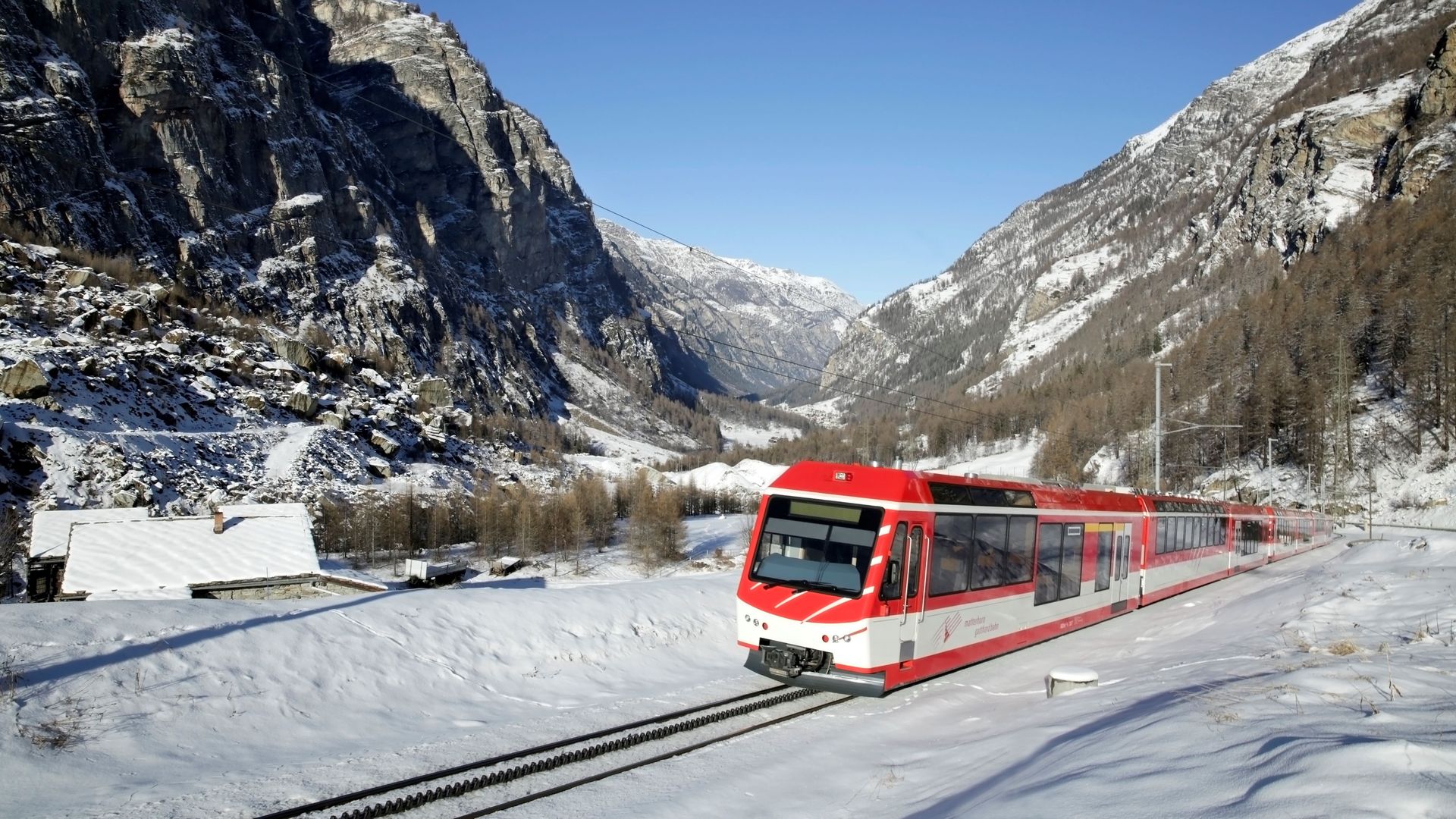 The Matterhorn Gotthard Bahn heads towards Zermatt, passing through the municipality of Randa, while the landscape is covered in snow.