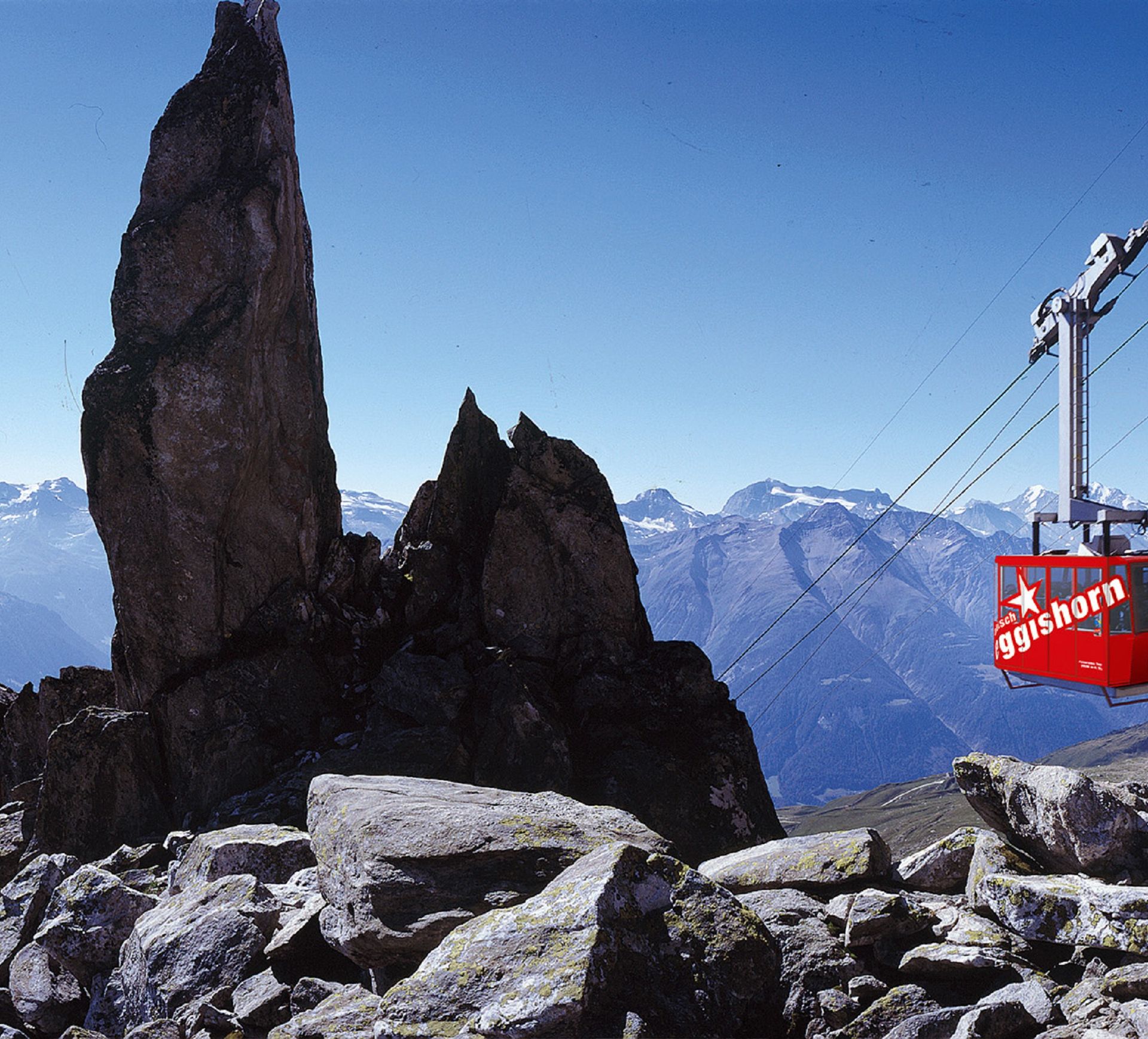 Die rote Eggishorn-Seilbahn erhebt sich in einer Berglandschaft unter einem klaren blauen und wolkenlosen Himmel.