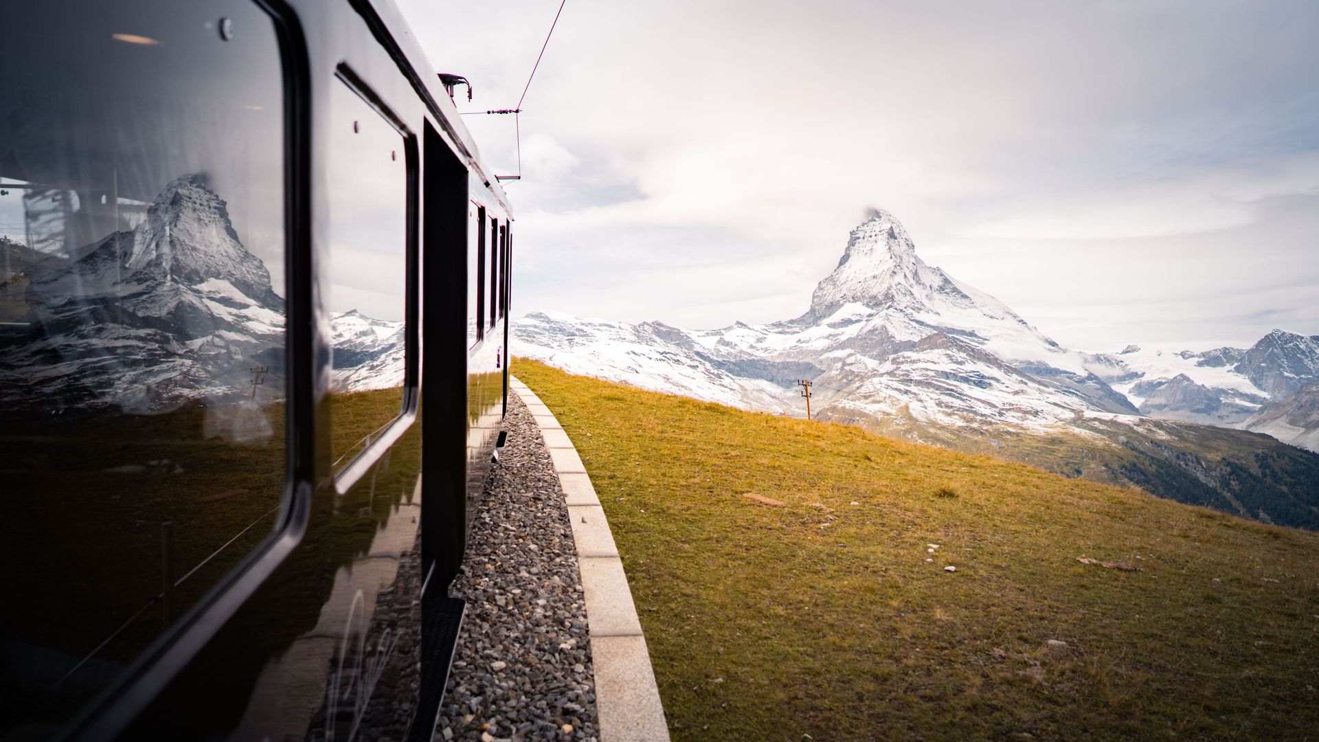 The NostalChic Class carriage travels towards the Matterhorn under partly cloudy skies in the fall season.