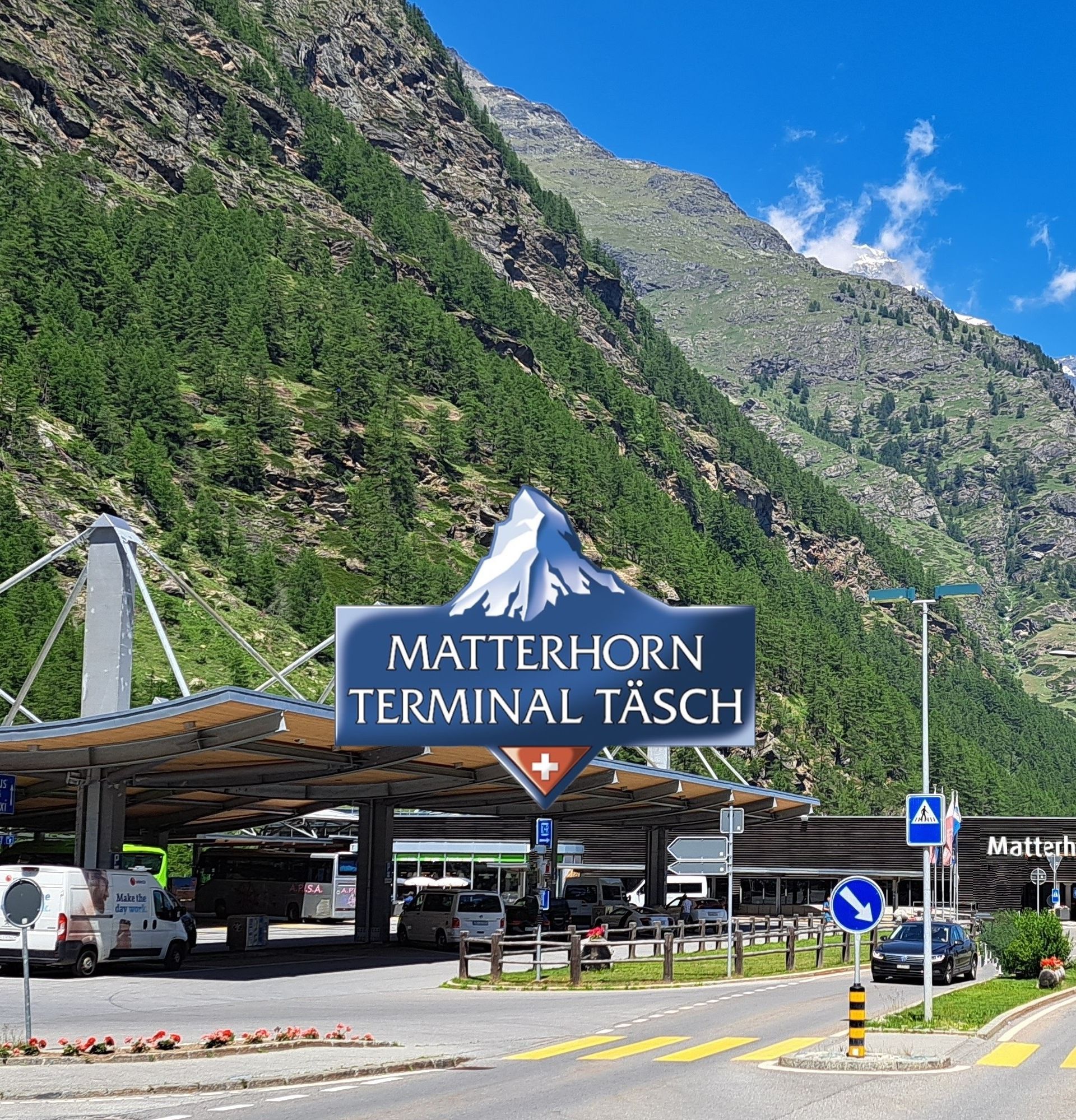 Terminal Matterhorn à Täsch en été, avec en arrière-plan les montagnes et un ciel bleu.
