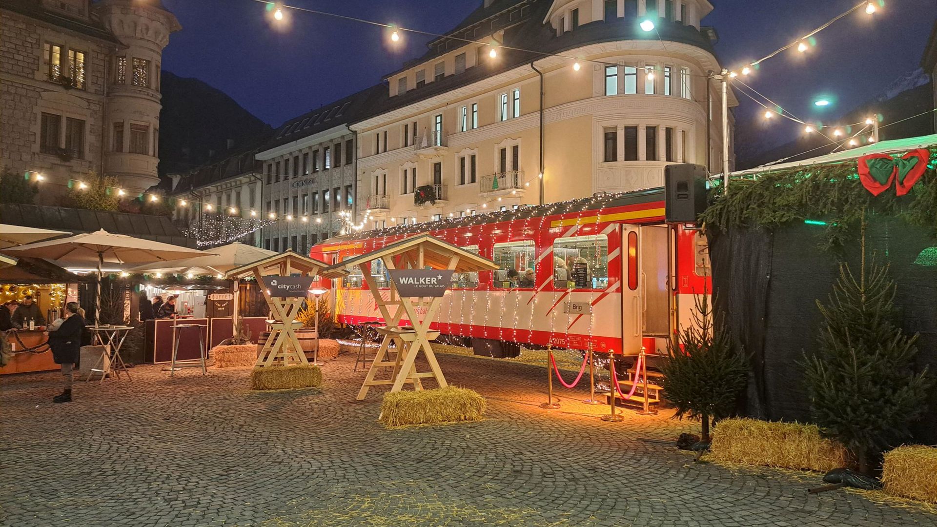 The Matterhorn Gotthard Bahn Christmas train, red and decorated with lanterns, in Brig during the Christmas market.