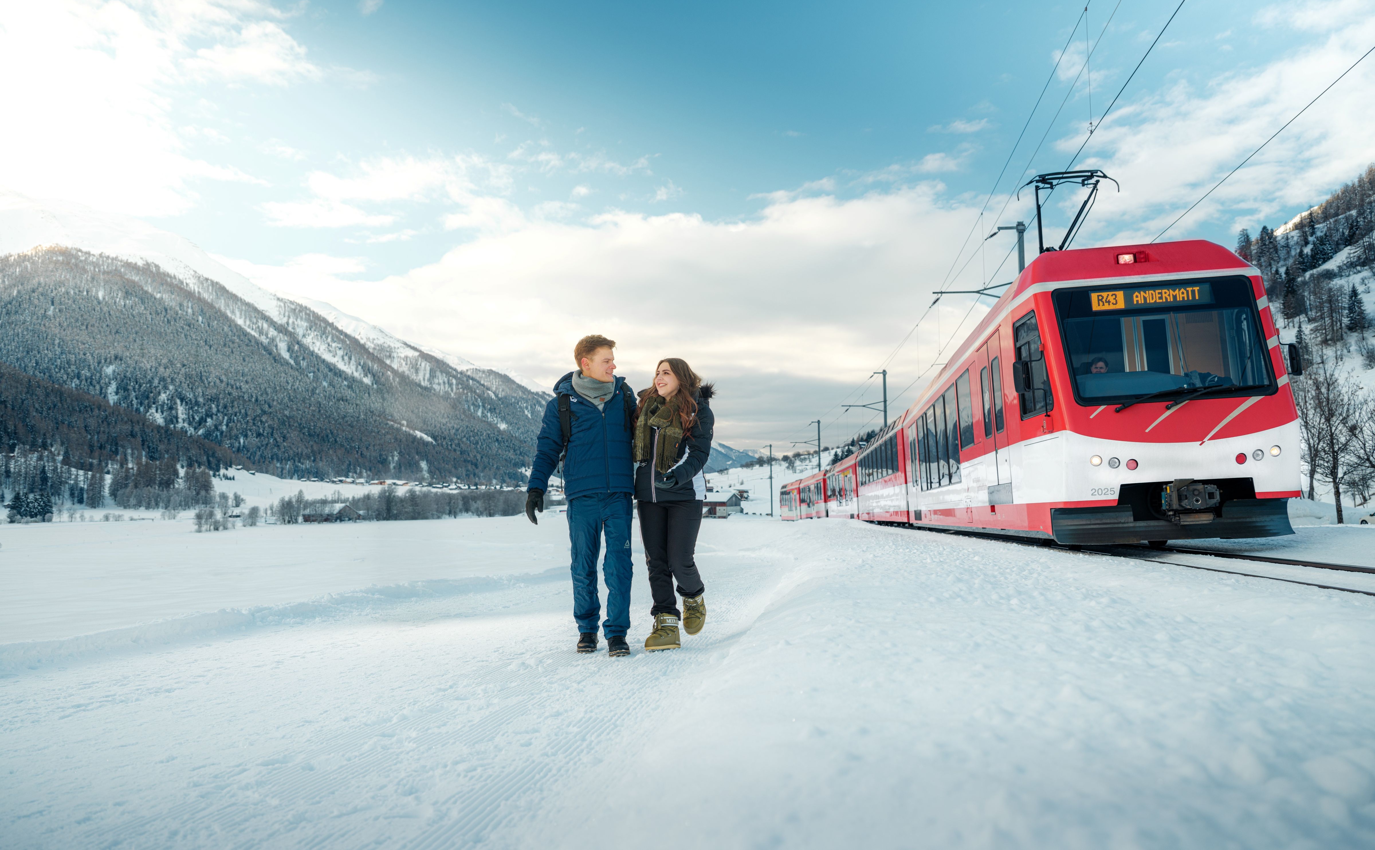 Two people hike through the snow in Goms